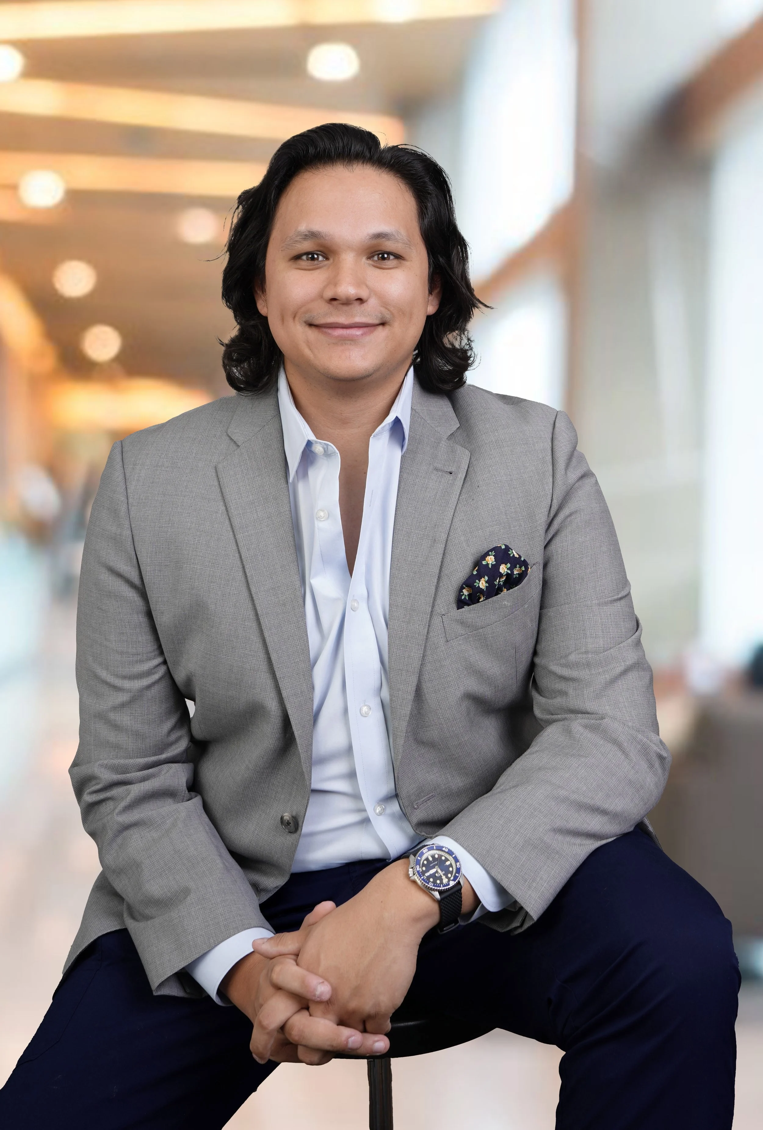 A young man poses for a professional business headshot with a virtual office background that gives it a modern look in the Raleigh photography studio
