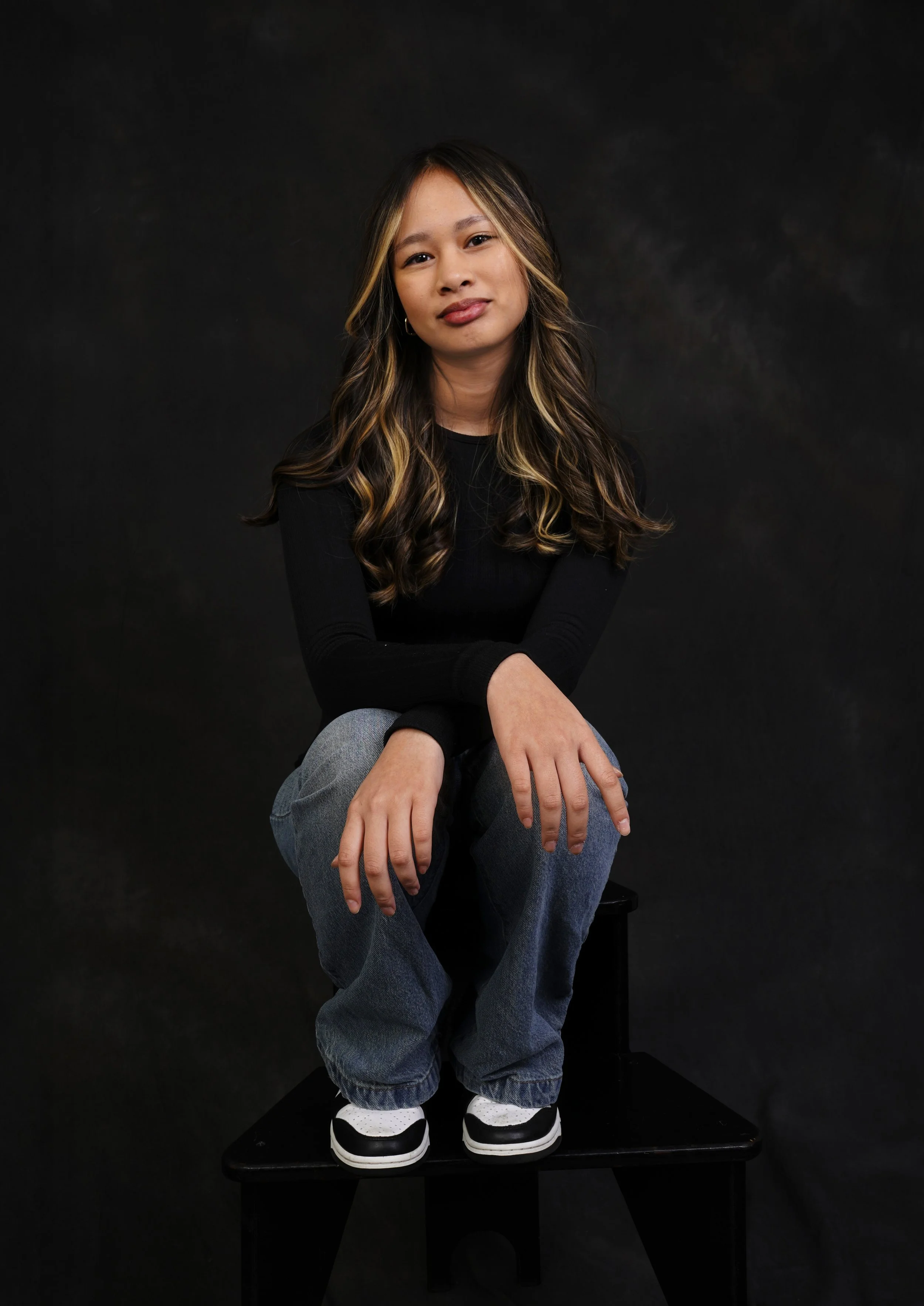 A woman's kids casting photo taken in a black shirt and jeans in Raleigh photography studio for modeling and acting portfolios against a black background.