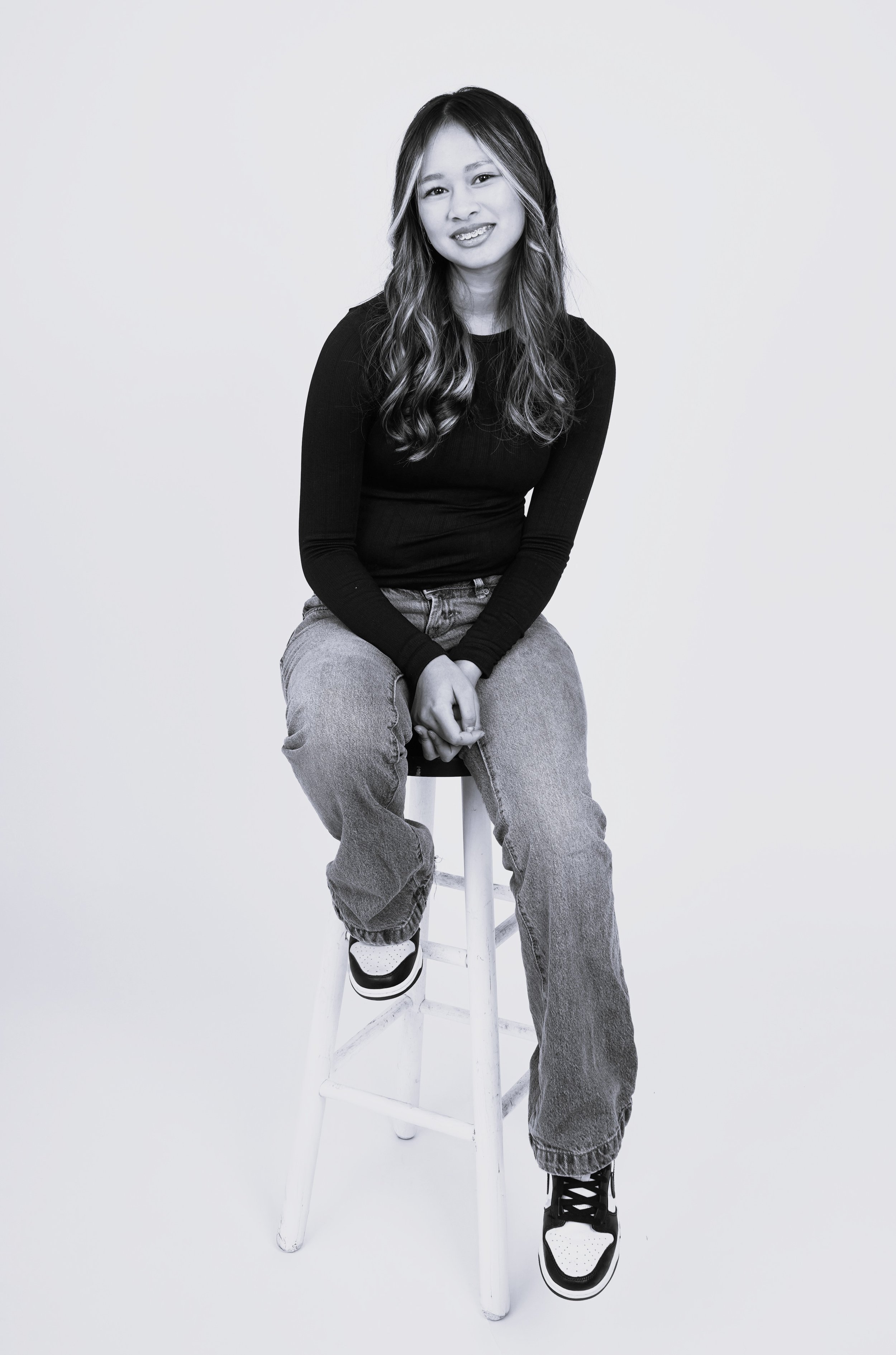 A black and white photo of a woman's kids casting photo taken in a Raleigh photography studio for modeling and acting portfolios while sitting on a stool