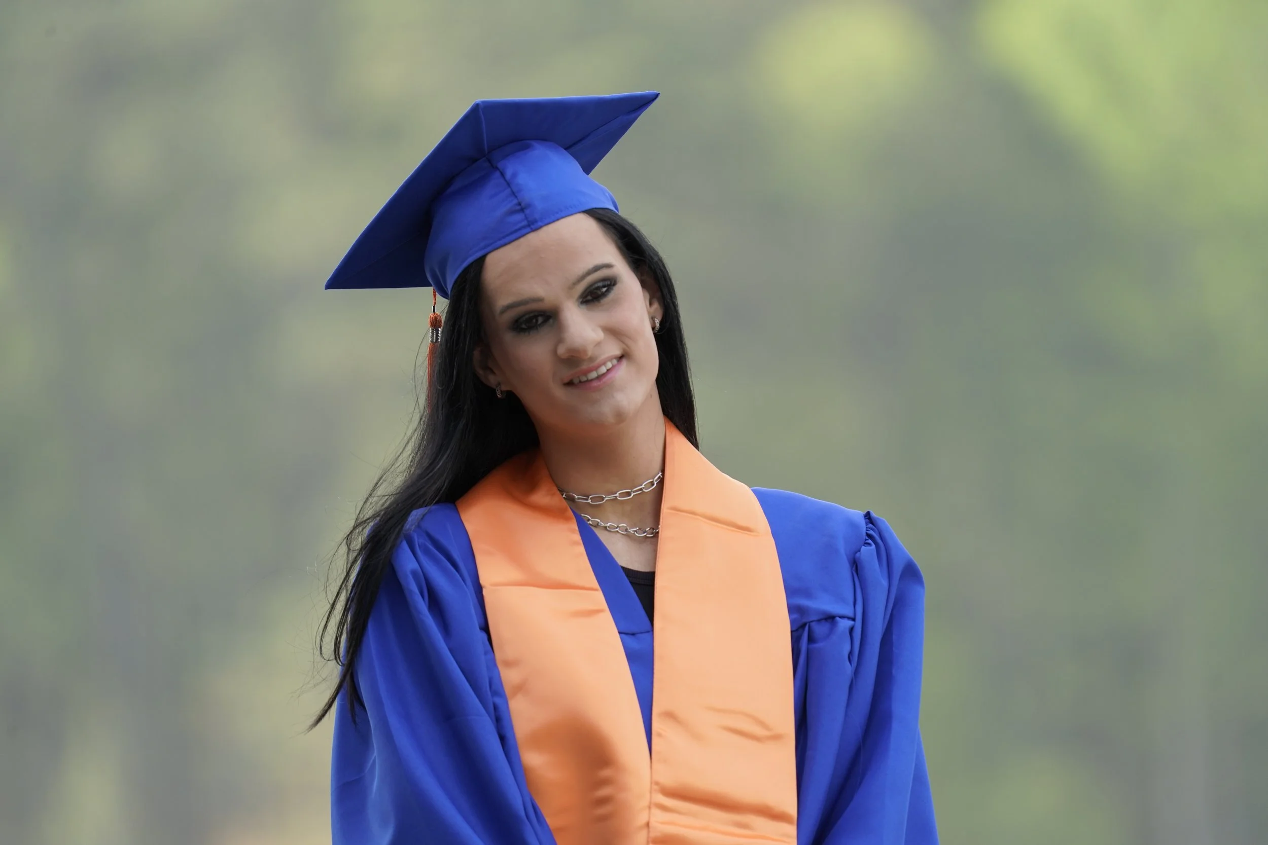 A woman stands in her graduation regalia at Lake Crabtree for her senior photos, Raleigh, North Carolina. High School Senior Photography.