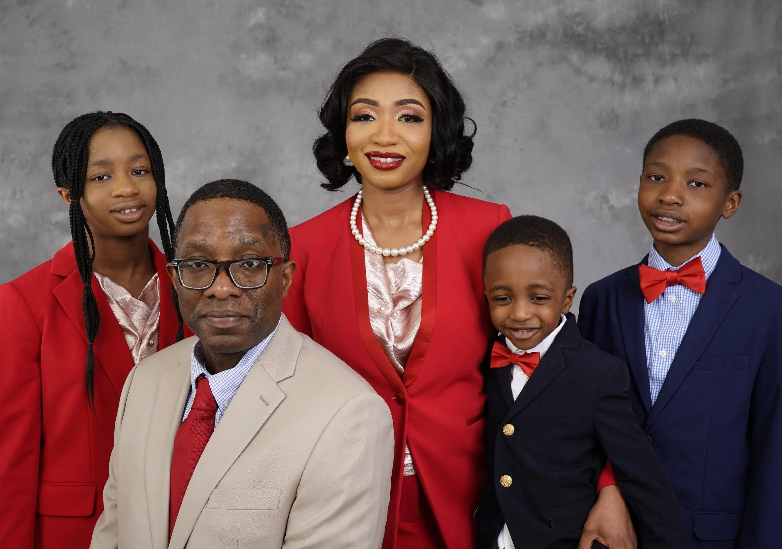 A family poses for in Raleigh studio photos in a theme of red suits and fancy outfits