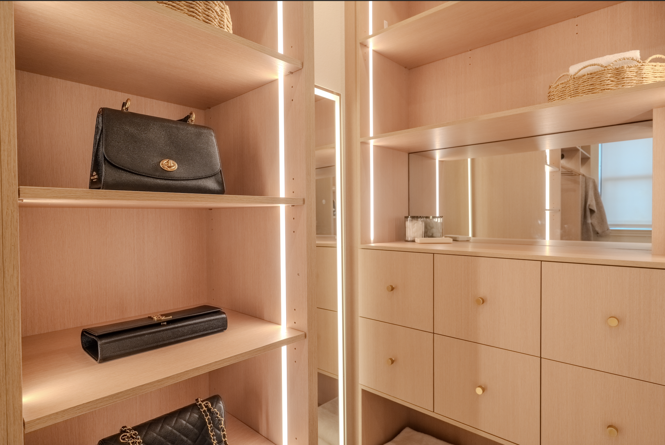A wooden closet with shelves holding handbags, a purse, and decorative baskets with textiles, illuminated with integrated lighting.