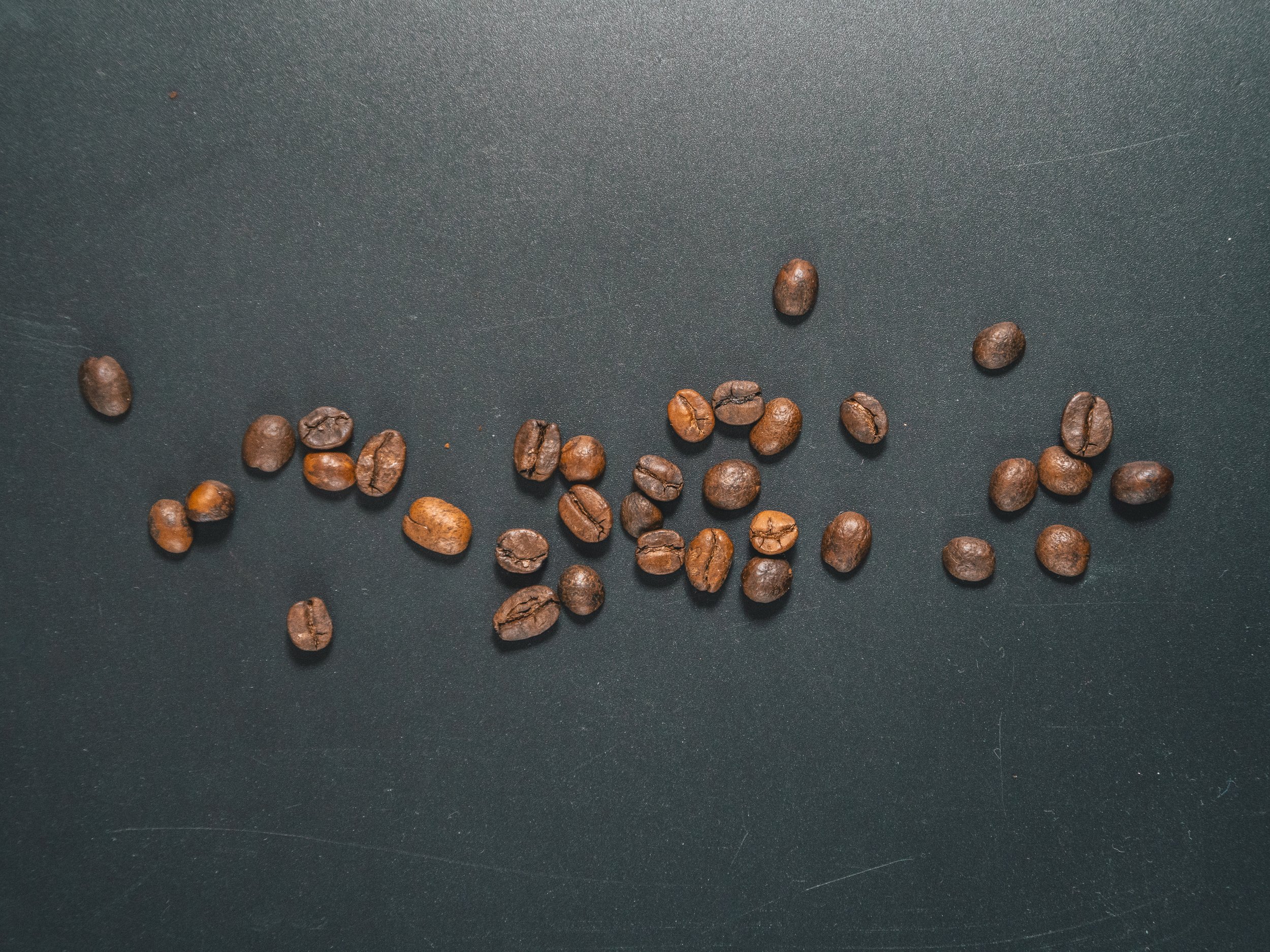 Coffee beans scattered on a black surface.