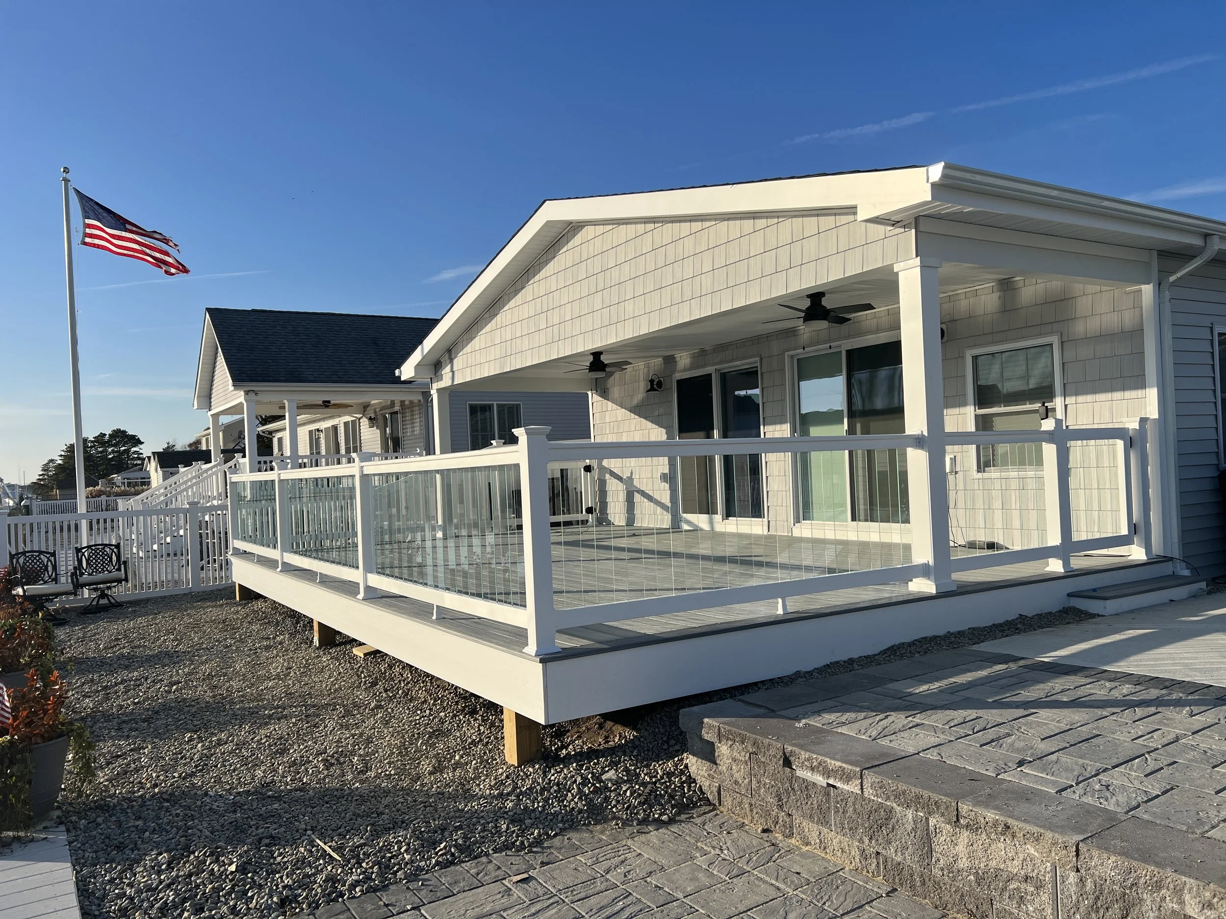 Jersey Shore home exterior with custom white deck and glass railings by Coastal Creations.
