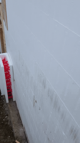 Close-up of a white wall with visible dirt marks and a partially seen red and white fire extinguisher label.