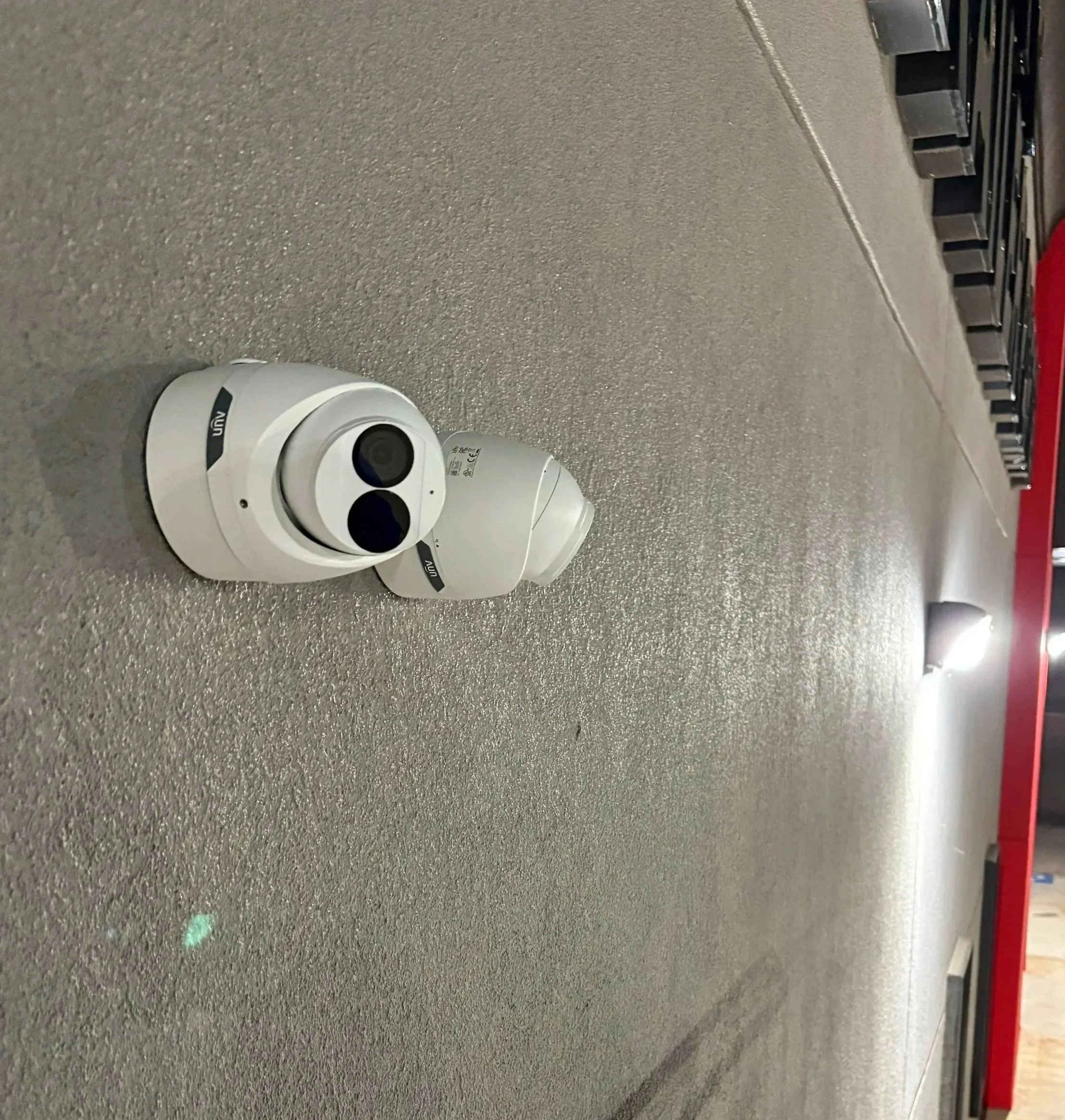 A white security camera with dual lenses resting on a gray speckled countertop.