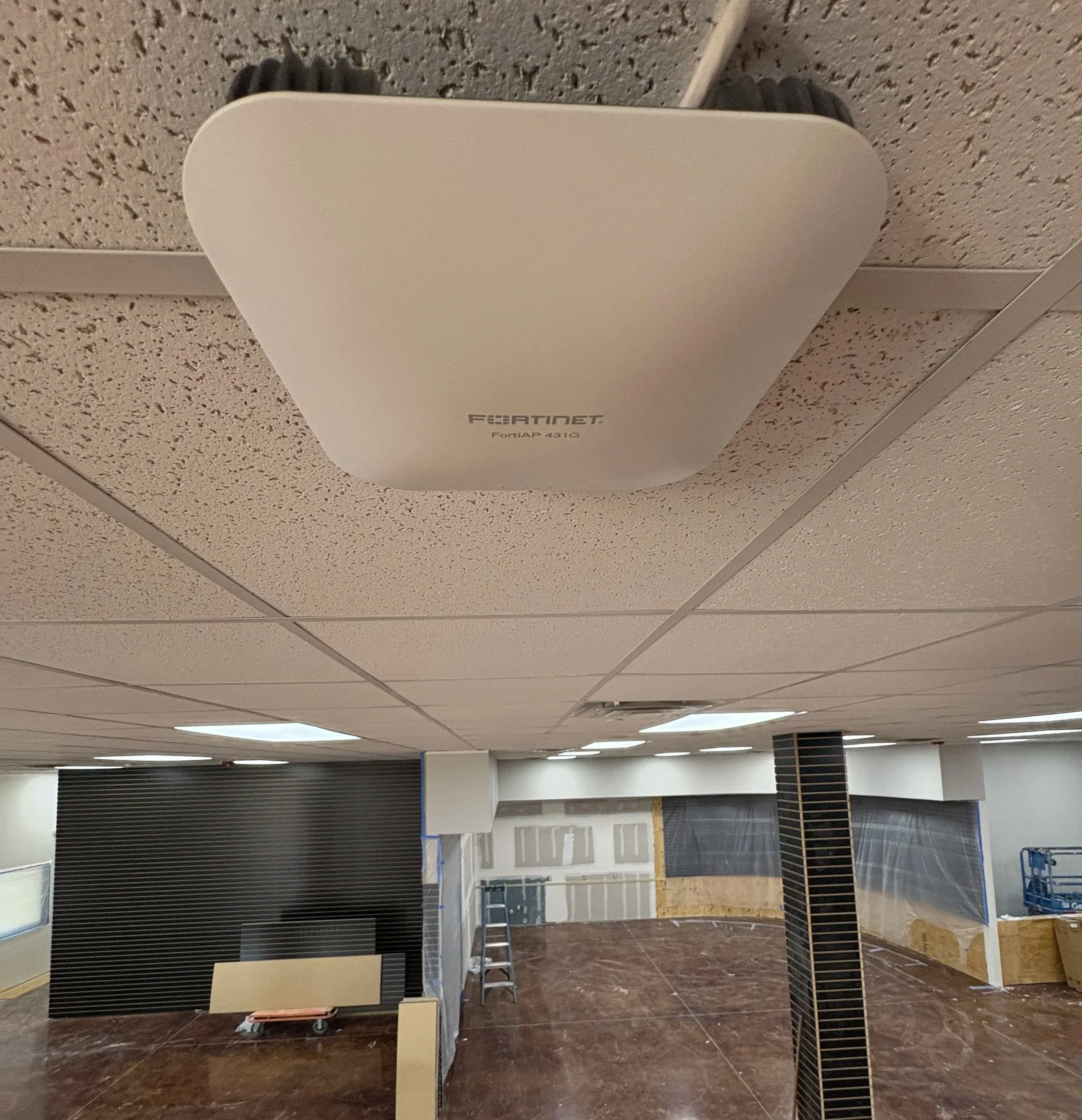 Ceiling-mounted Fortinet FortiAP 431G wireless access point in a commercial or office space under construction or renovation.