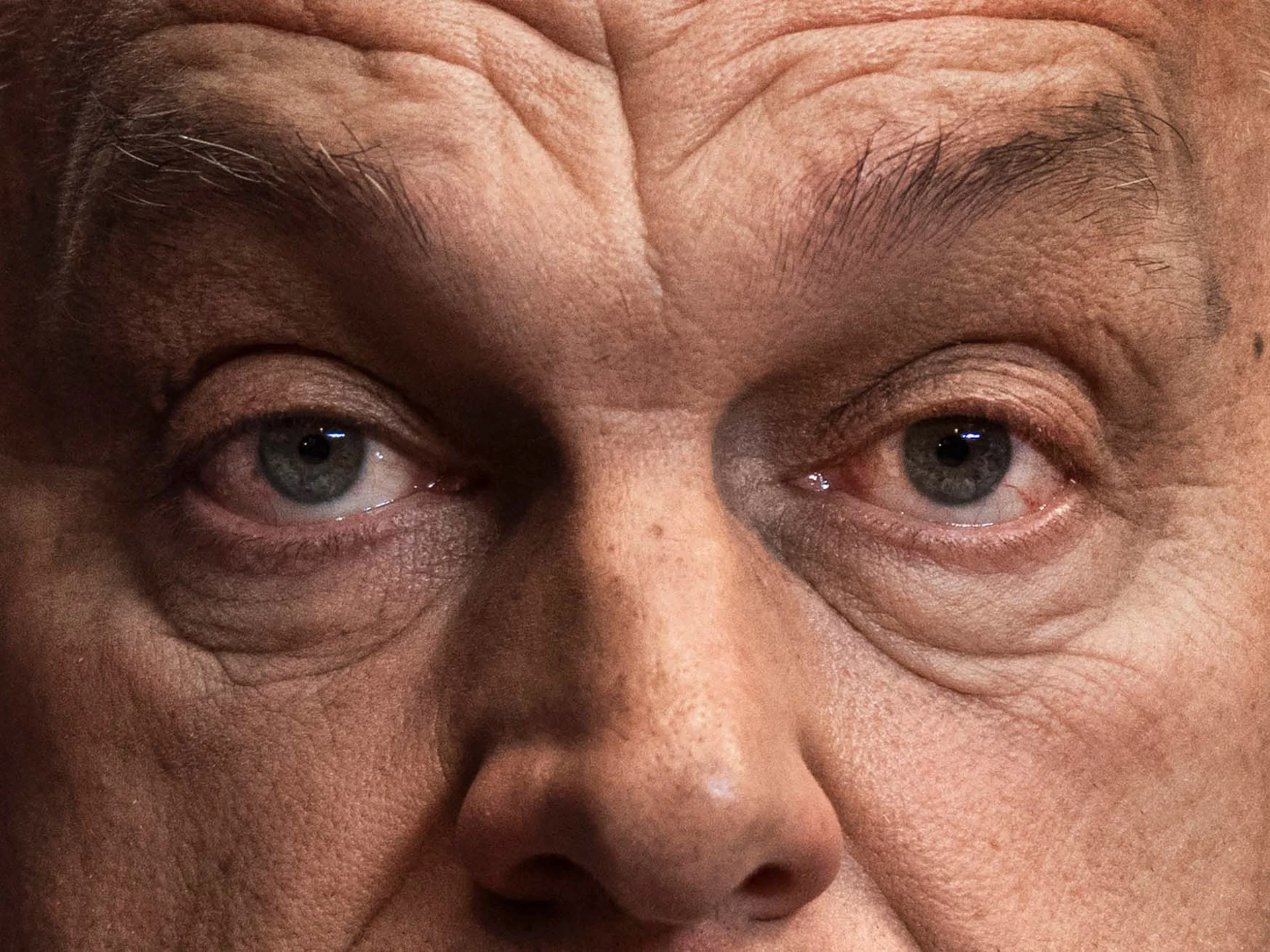 Close-up portrait of an elderly man's blue-gray eyes, forehead, and facial wrinkles