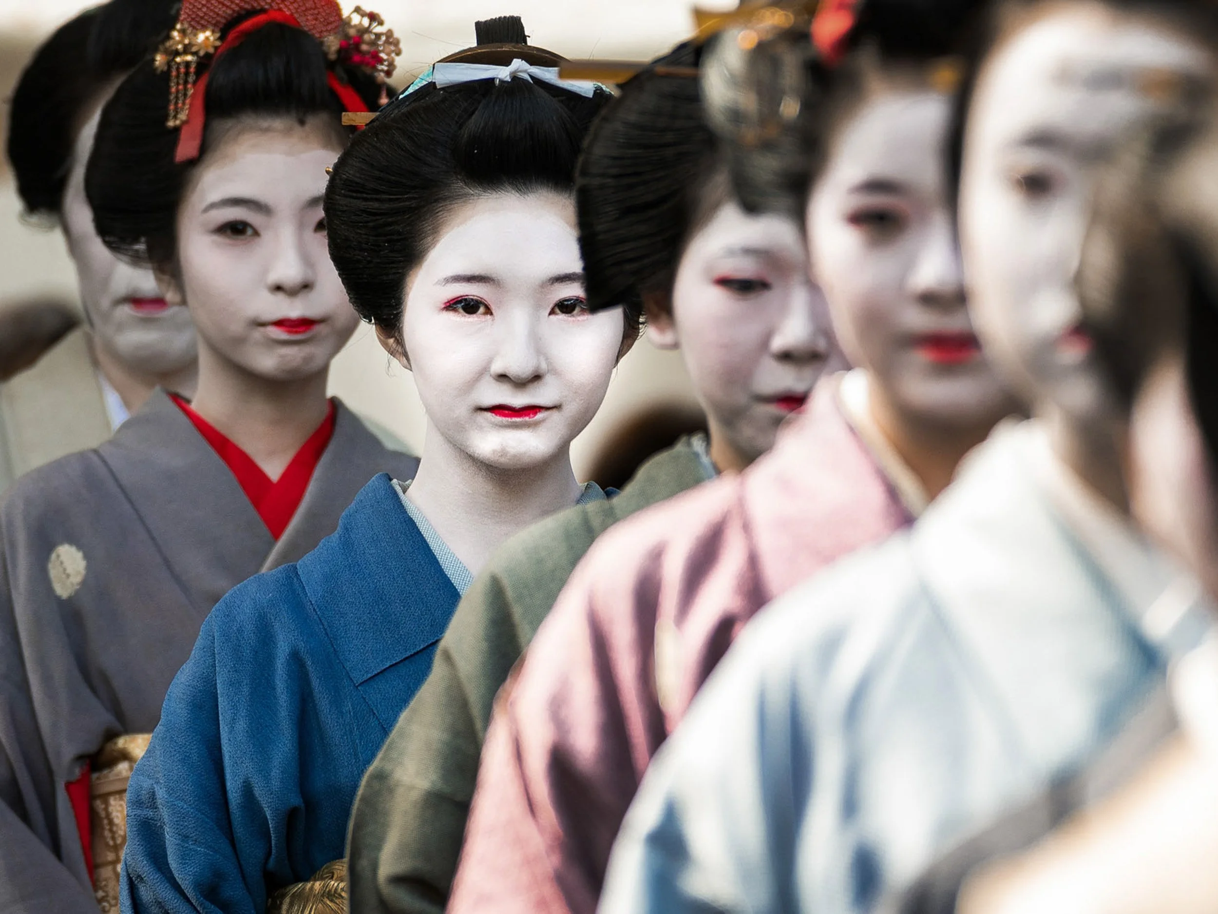 Geisha women in traditional Japanese kimono and elaborate hairstyles standing in a line