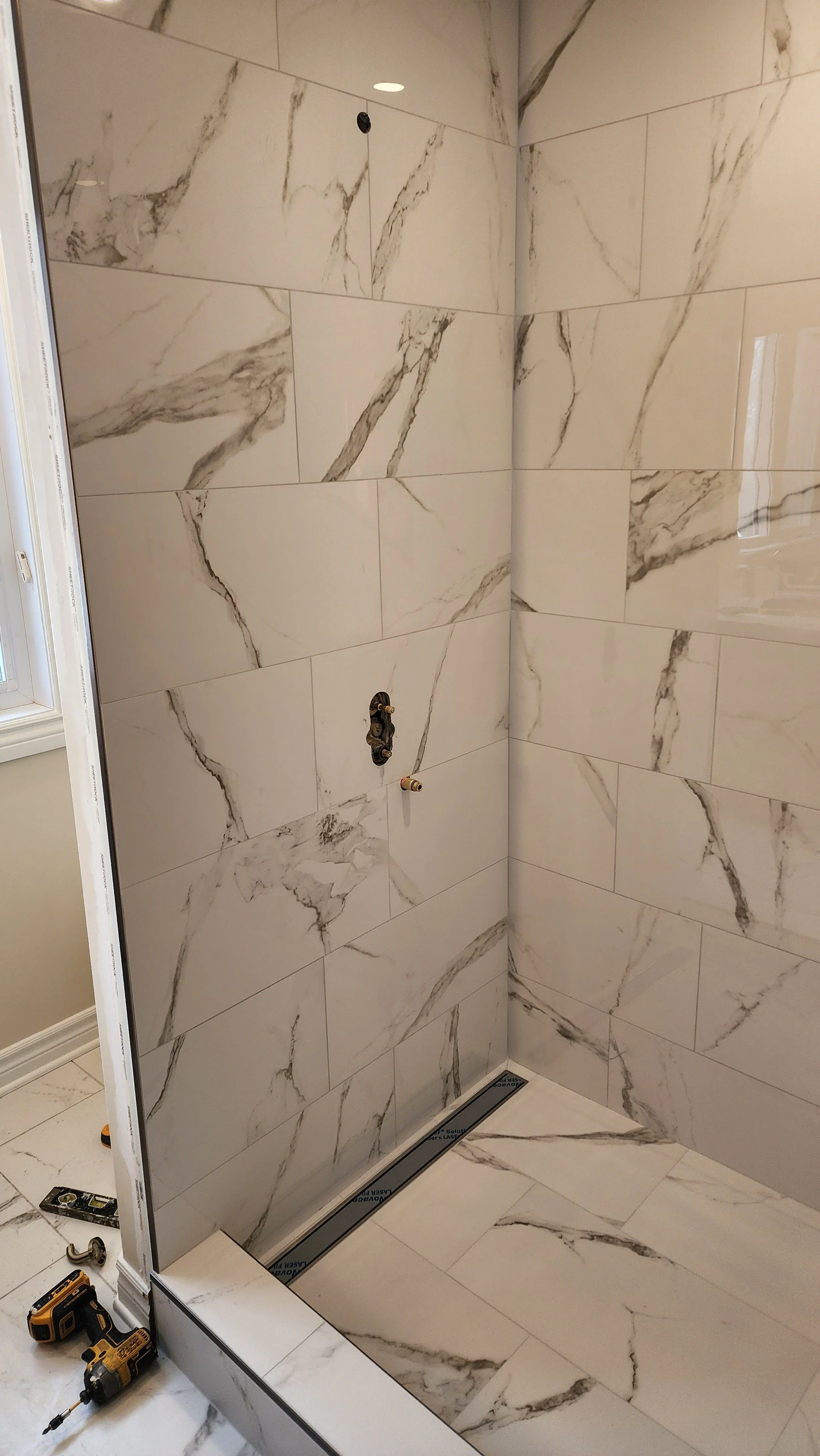 Marble-tile shower under construction with tools on the floor.