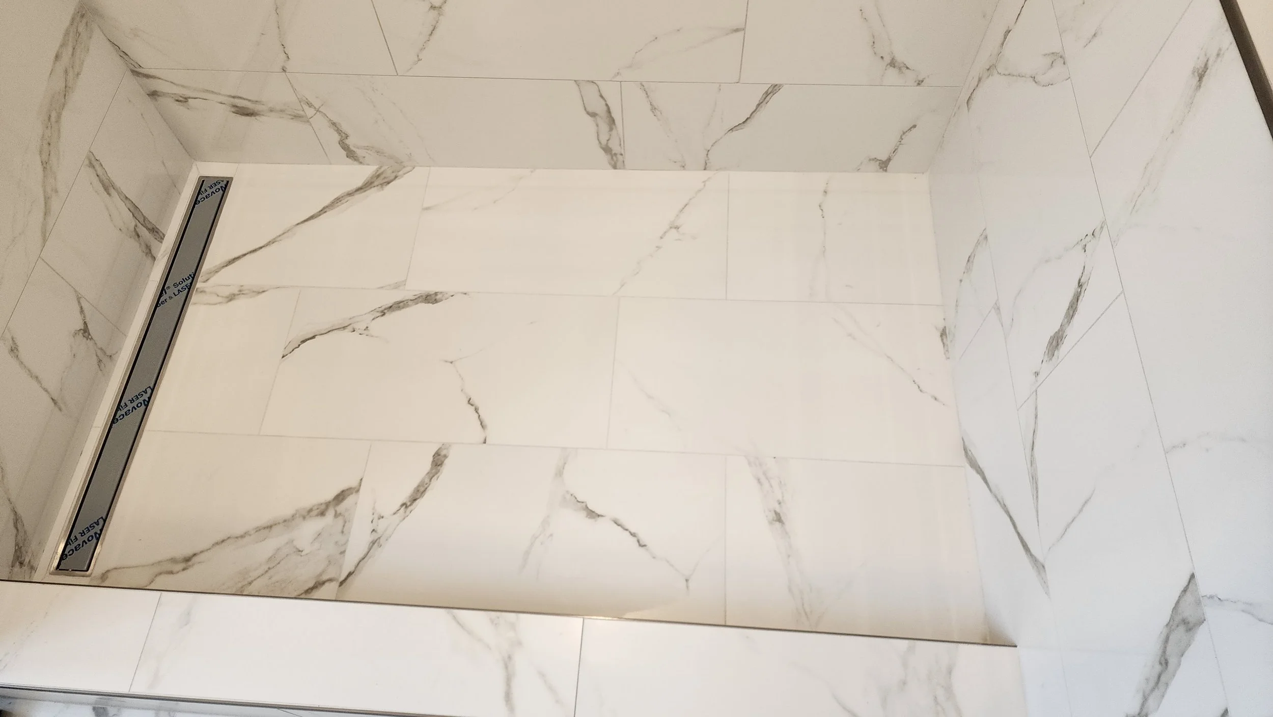 Marble tiled shower wall and floor with built-in recessed shower shelf.