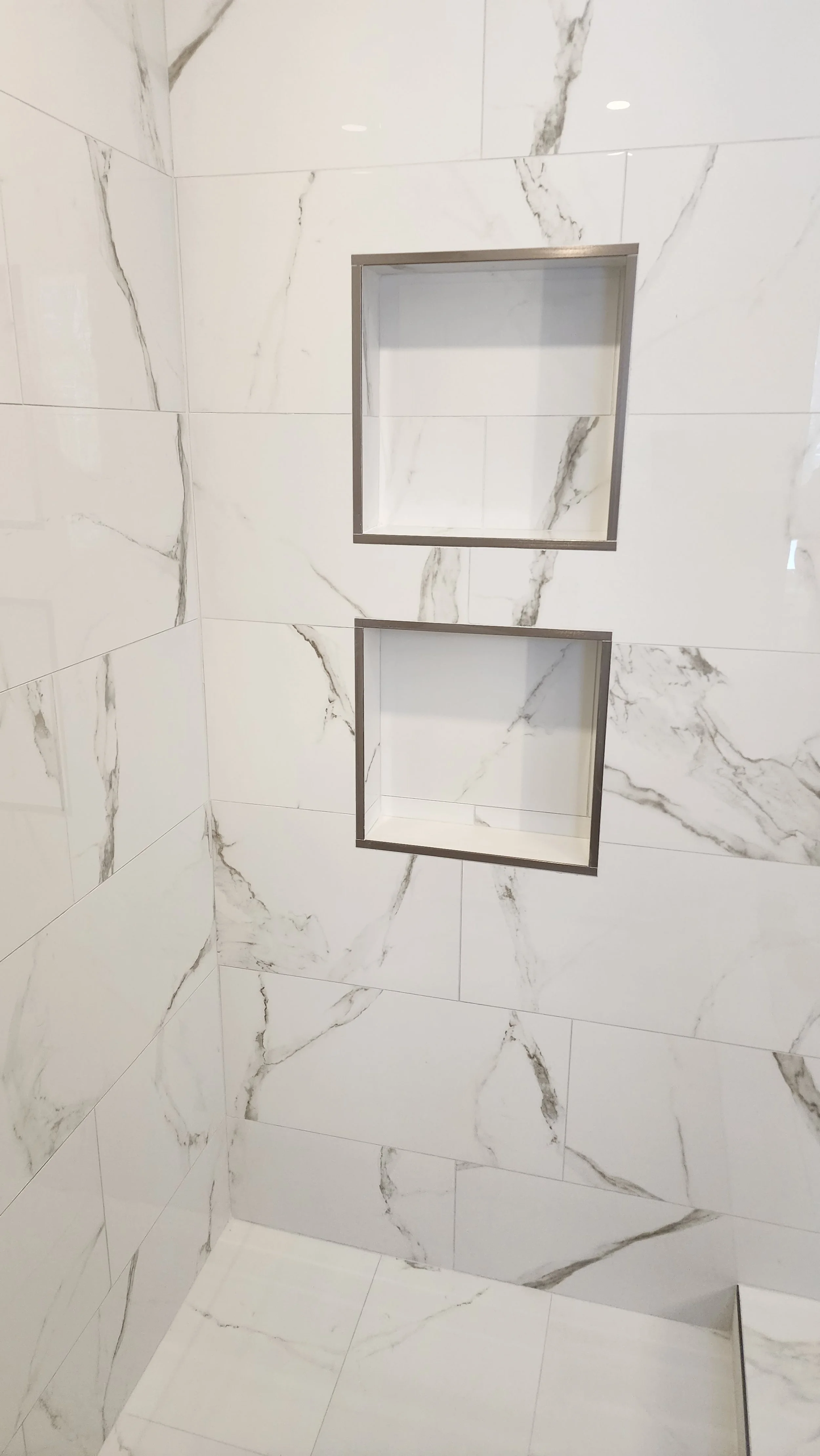 Marble tiled shower with two built-in shower niches.