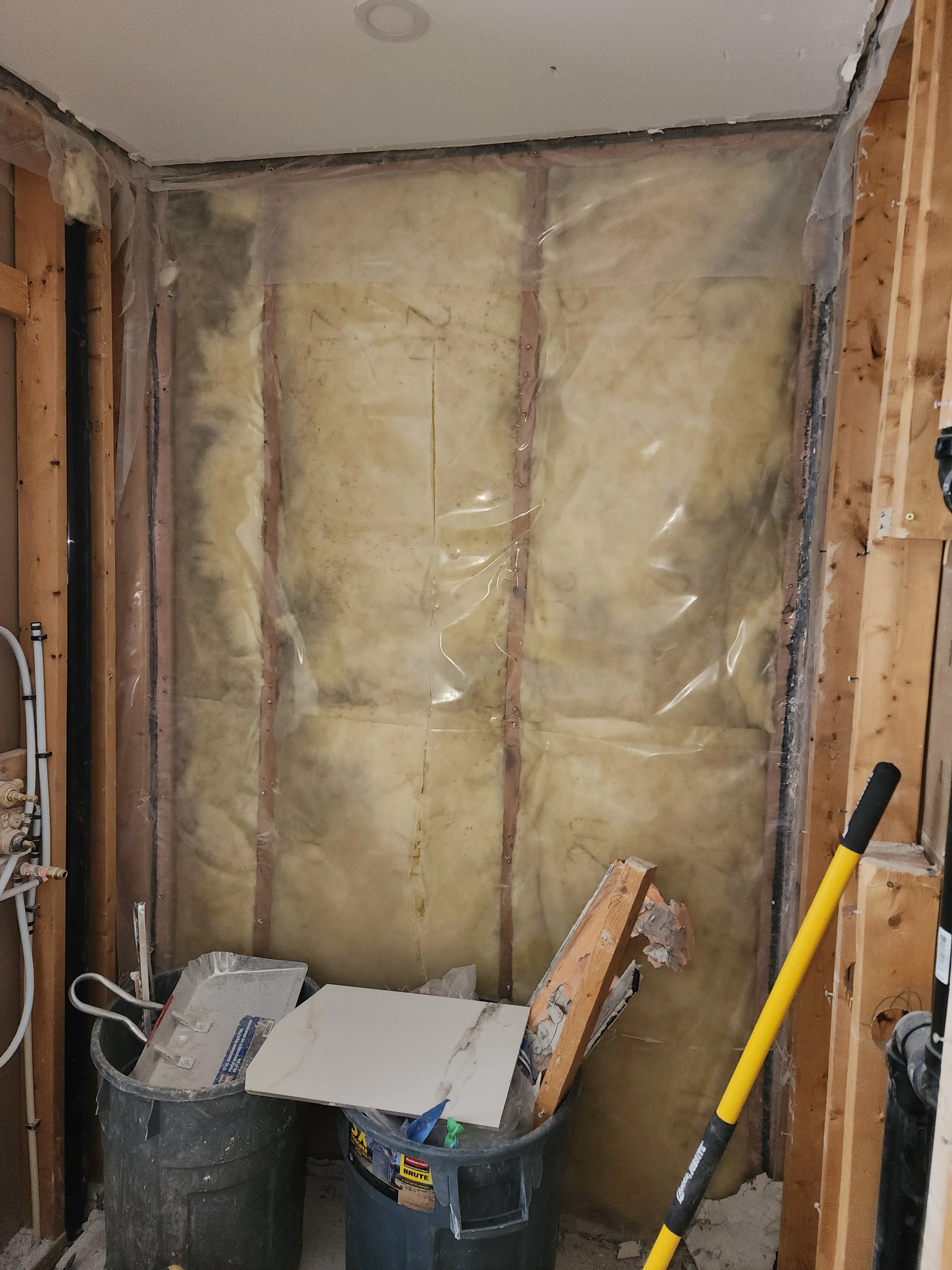 Interior wall under renovation with insulation, construction debris, and tools.