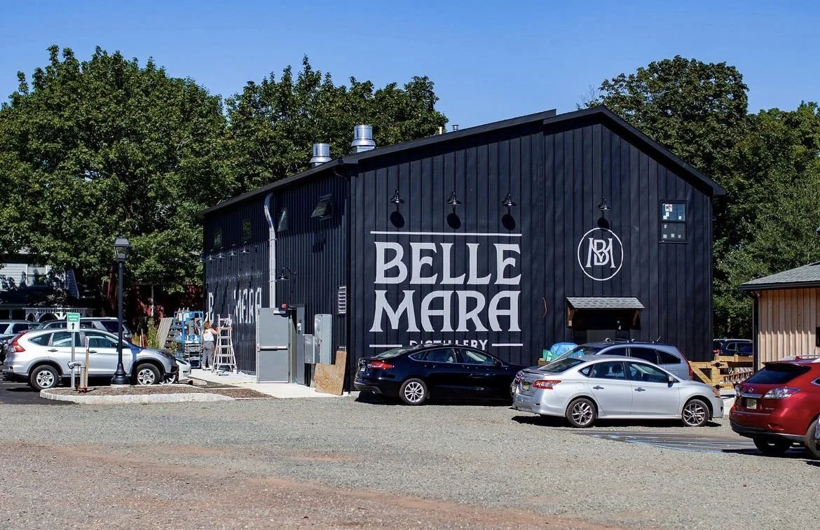 Black building with large signage reading 'BELLE MARA', surrounded by parked cars and trees in the background.