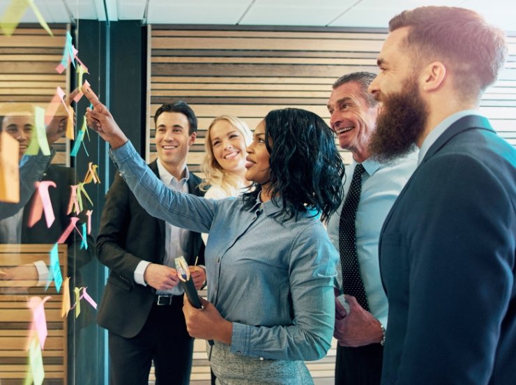 Group of business professionals having a meeting and using sticky notes on a glass wall.