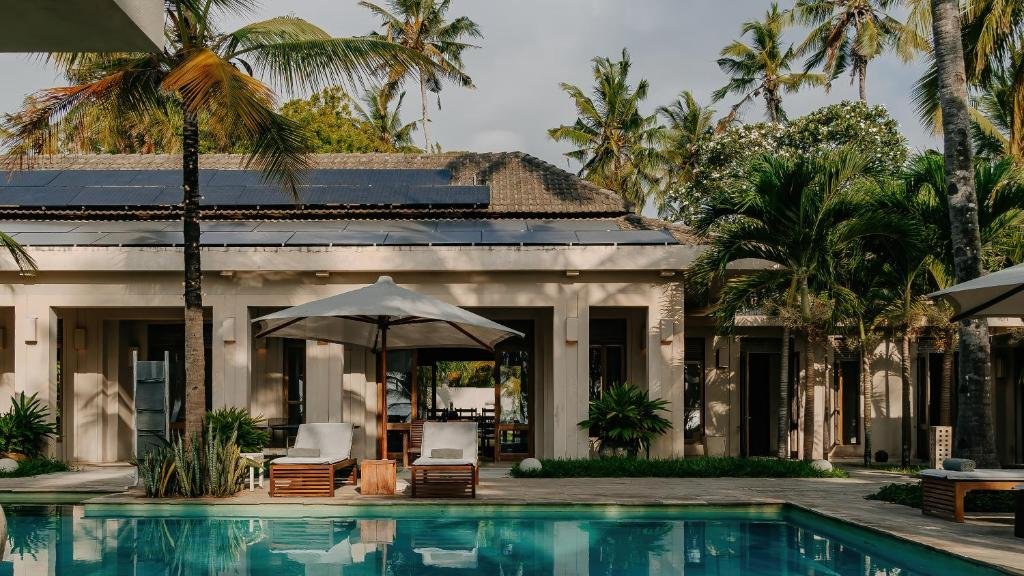 Luxury house with pool surrounded by palm trees and outdoor seating area with umbrellas