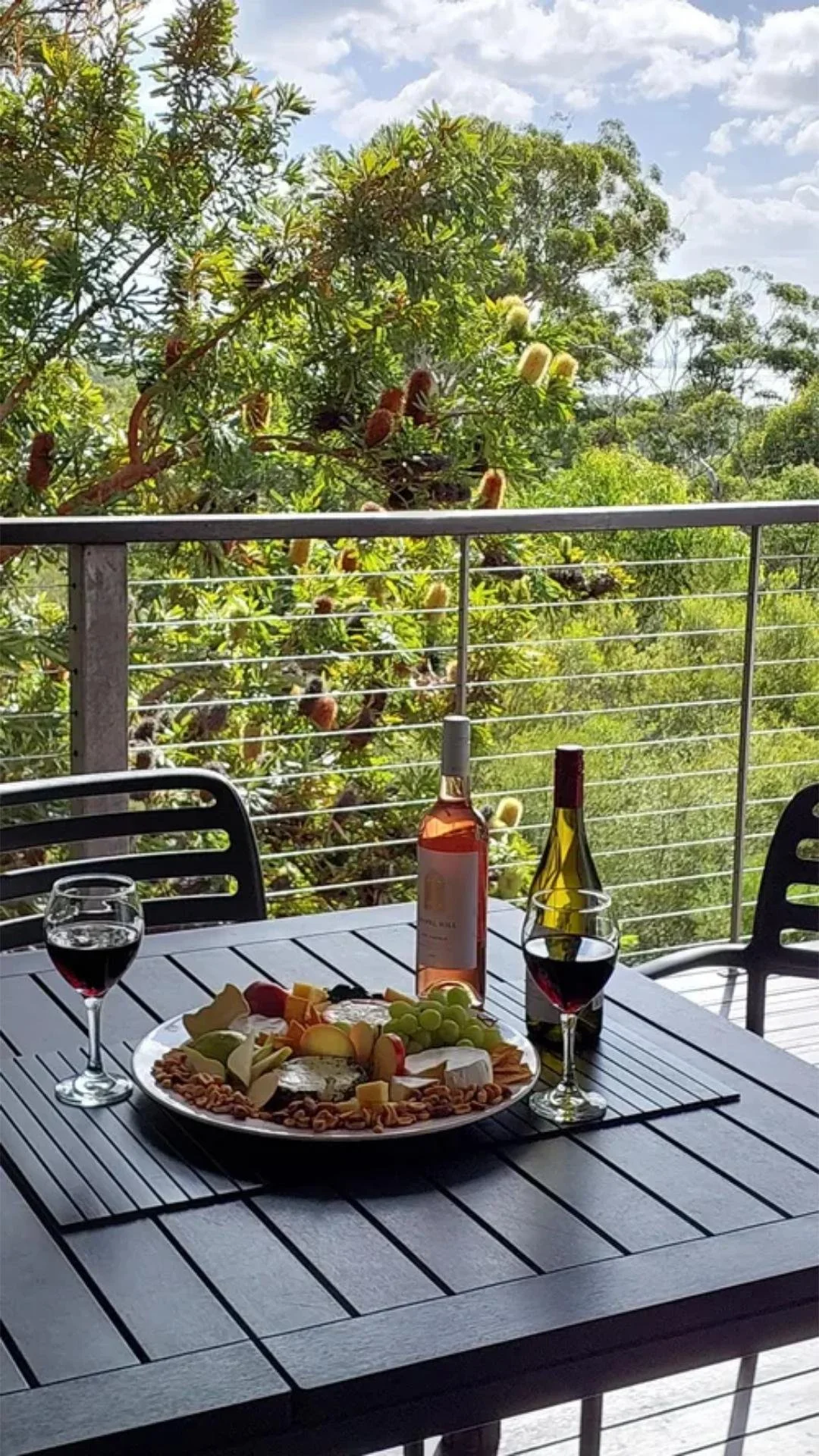 A welcoming table with a selection of cheeses, biscuits, and fruit fresh fruit, served with wine and glasses, overlooking a relaxing scenic view