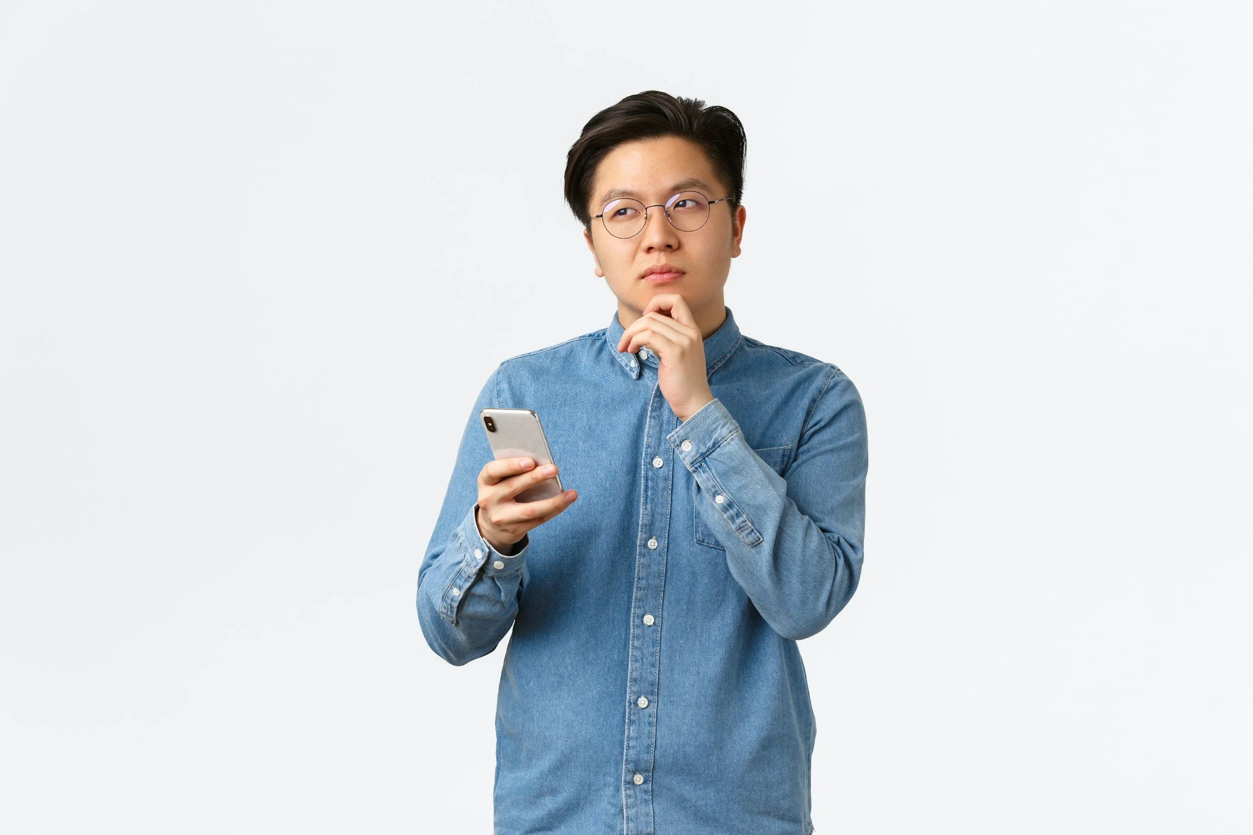 Person using a smartphone while thinking, representing how user intent and search behavior are becoming more important than keywords in SEO and AI search.