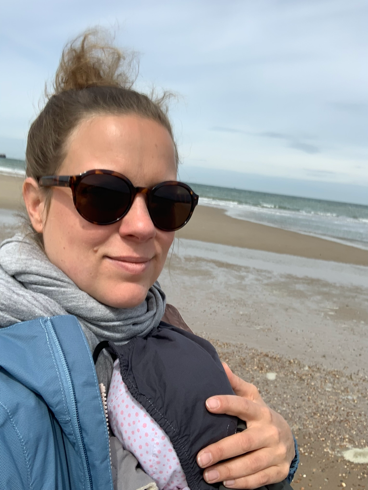 Mutter mit Kind in der Trage am Strand