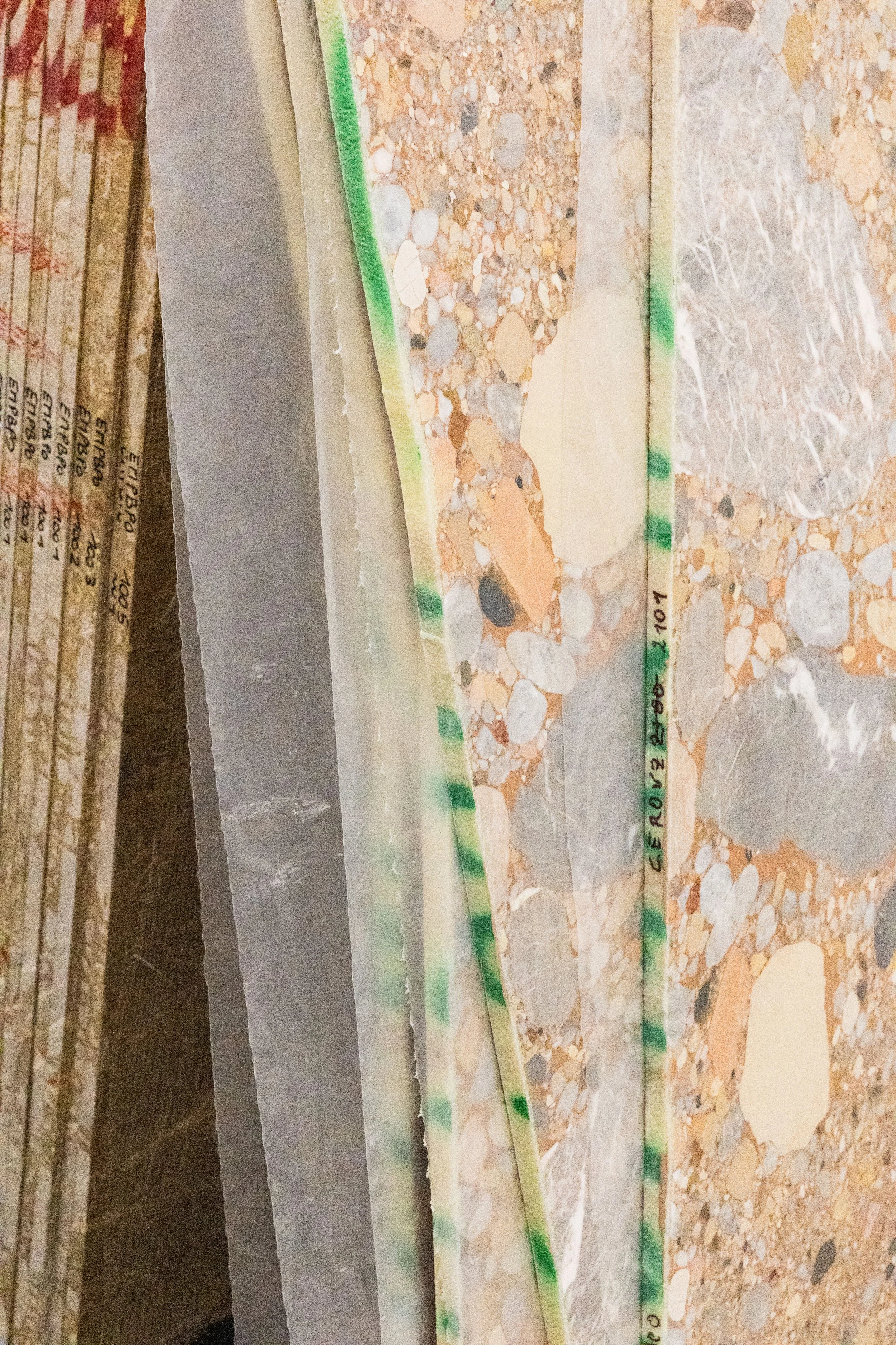 Close-up of a layered rock specimen with a green-striped mineral border, showing various mineral components and labels on the side.