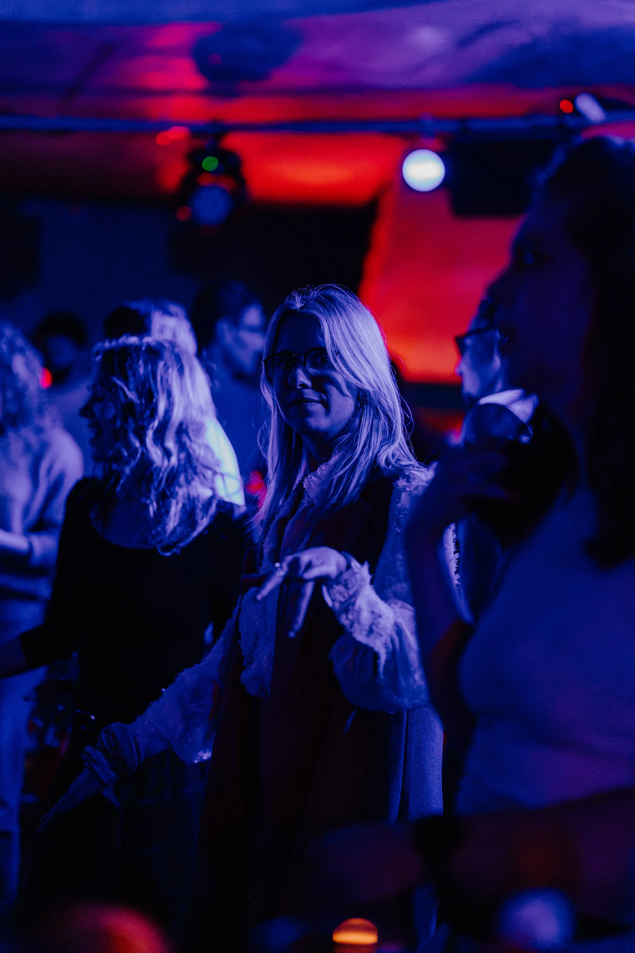 Mensen die naar een concert of clubshow kijken, gezien onder blauwe en rode verlichting.