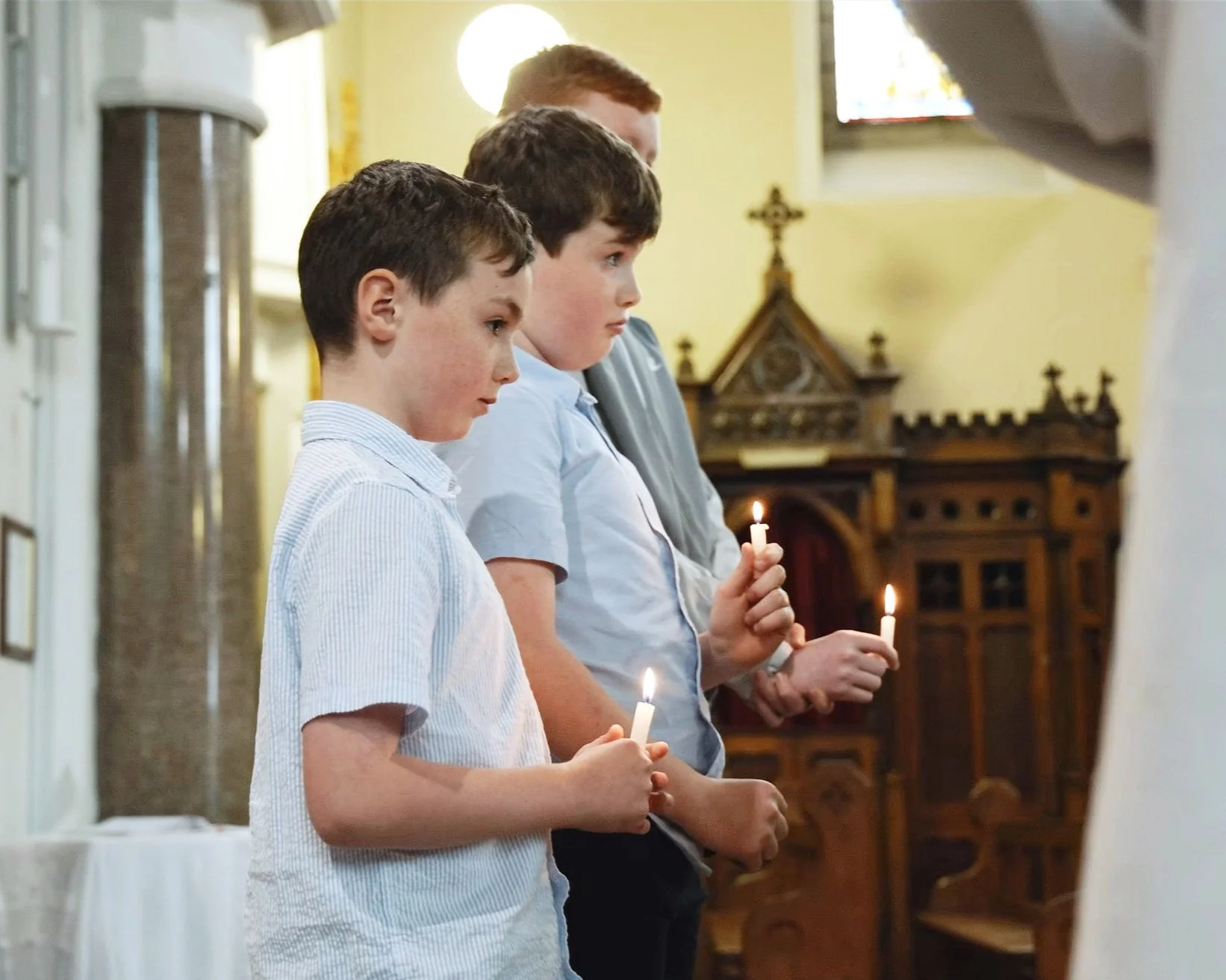 Šventės momentas – krikštas, berniukai laiko žvakutes