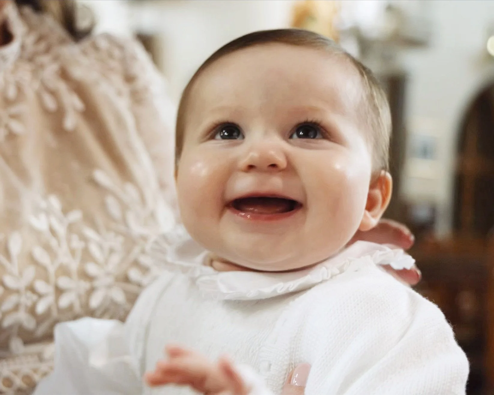 Krikštynų šventės akimirka – vaiko šypsena artimųjų apsuptyje