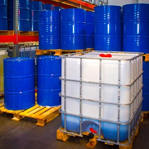 Blue hazardous waste industrial barrels and a large cube-shaped container on wooden pallets in a warehouse setting.