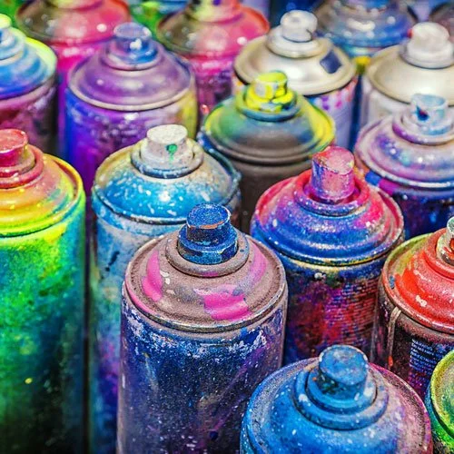 Colourful hazardous waste spray paint cans with artistically splattered paint.