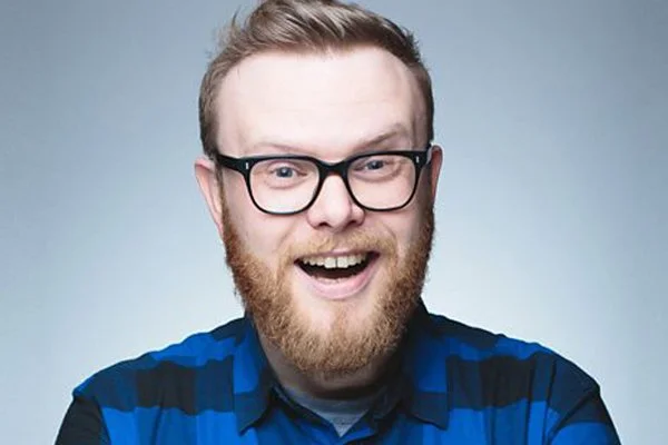 Huw Stephens, wearing a blue checkered shirt against a plain background.