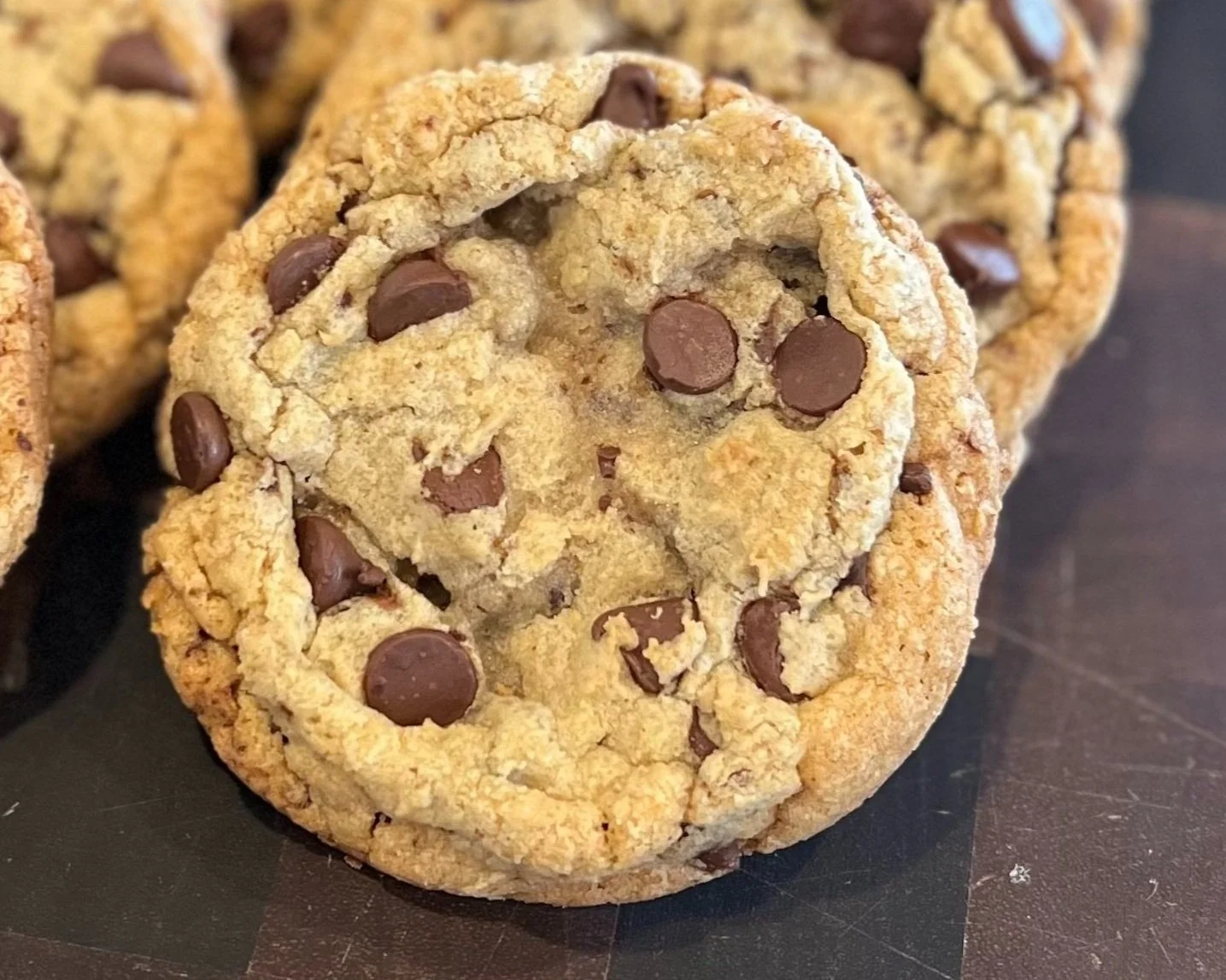 Close-up of chocolate chip cookies on a dark surface.