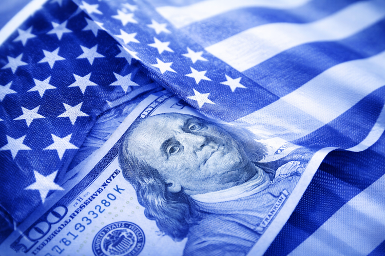 A US dollar bill resting on a waving American flag, tinted blue.