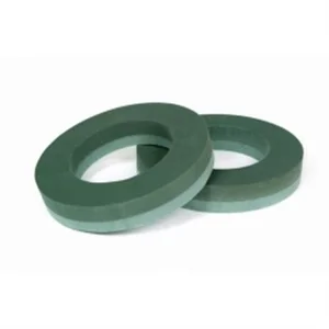 Two green florist oasis ring foam for a wreath, lying on a white surface.