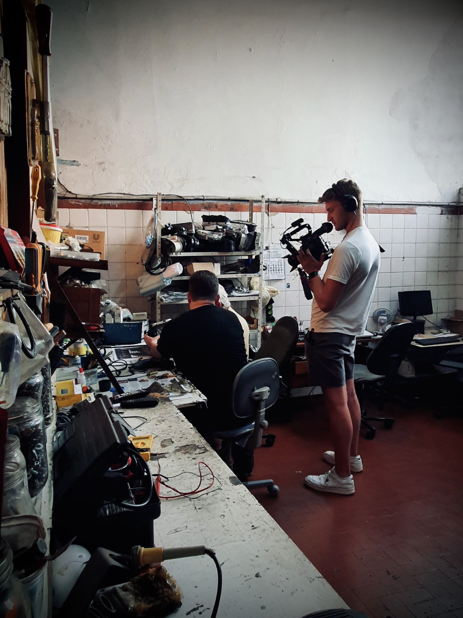 James filming in a workshop, capturing hands-on repair work at a workbench.