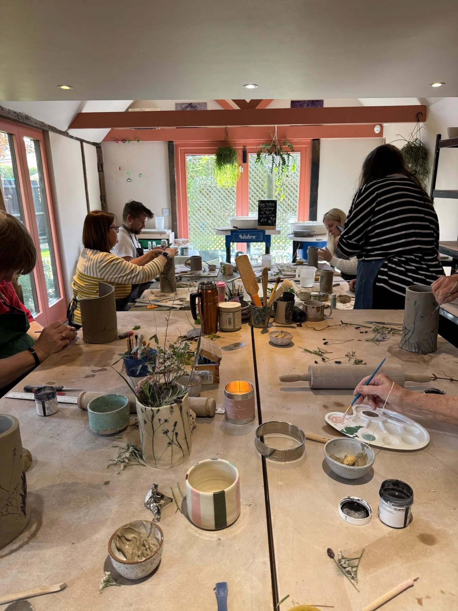 people in a studio making pottery vases with teacher