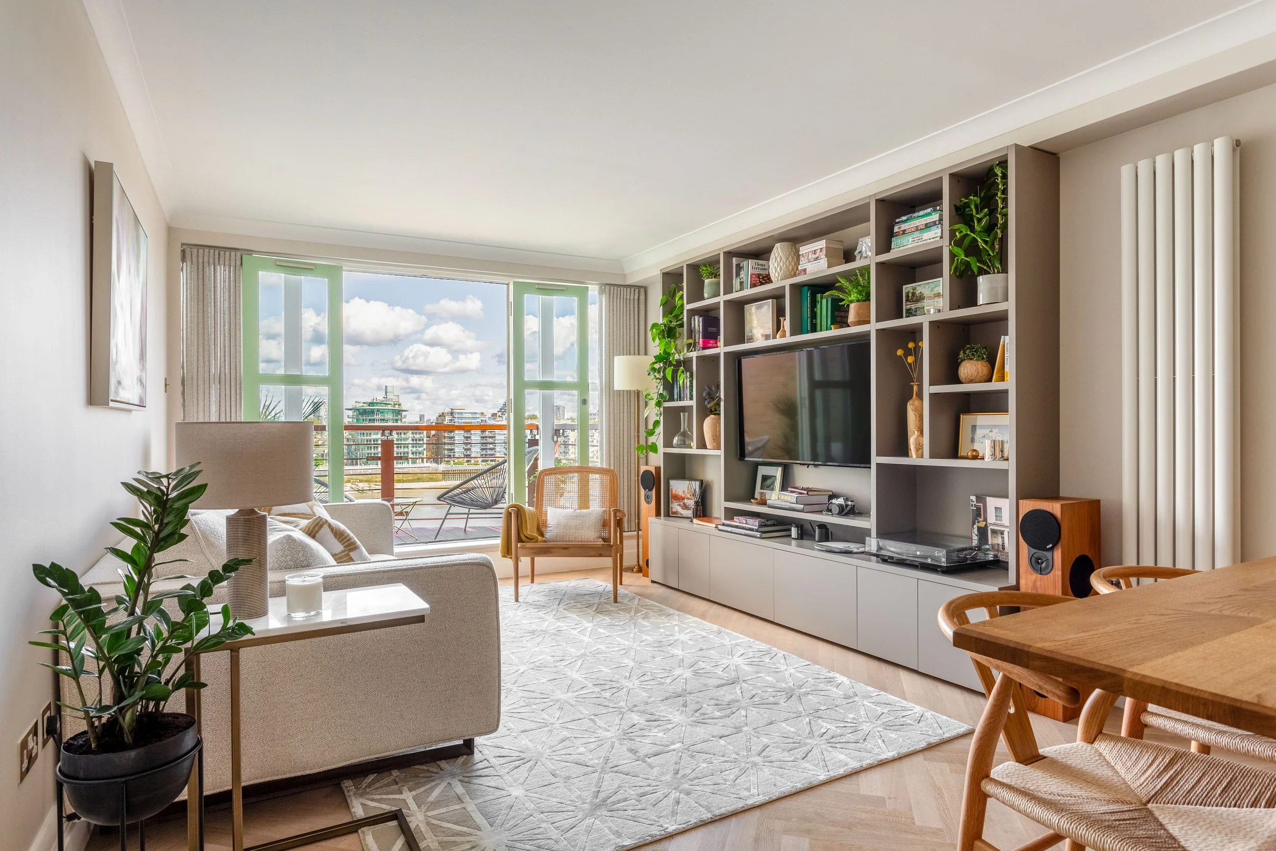 Small apartment open-plan living space with riverside balcony, built-in shelving and dining area combined for open plan living