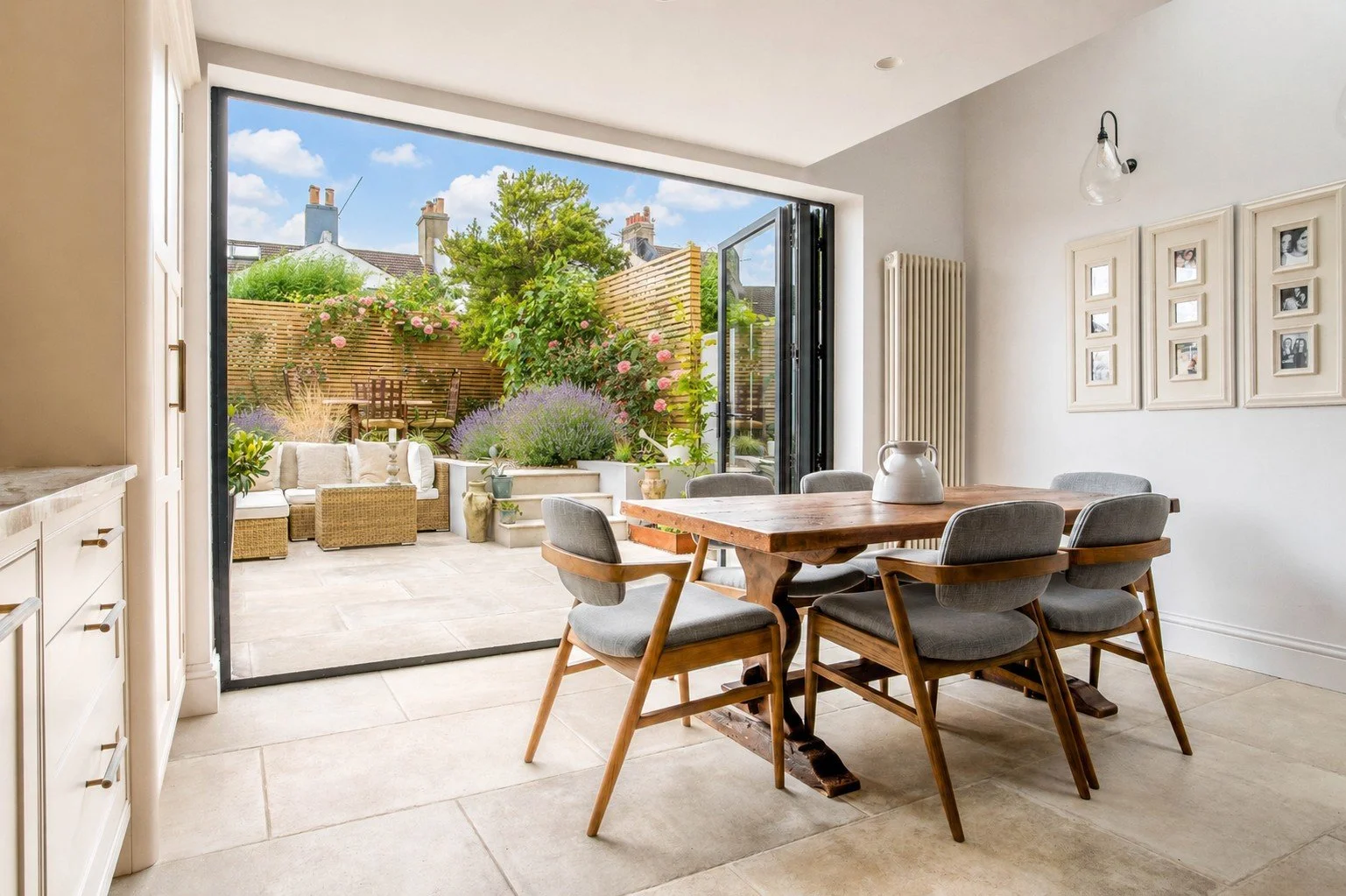 A bright, uncluttered dining area with expansive glass doors that open fully to a lush garden, blurring indoor-outdoor boundaries to reduce stress through natural light and biophilic design.