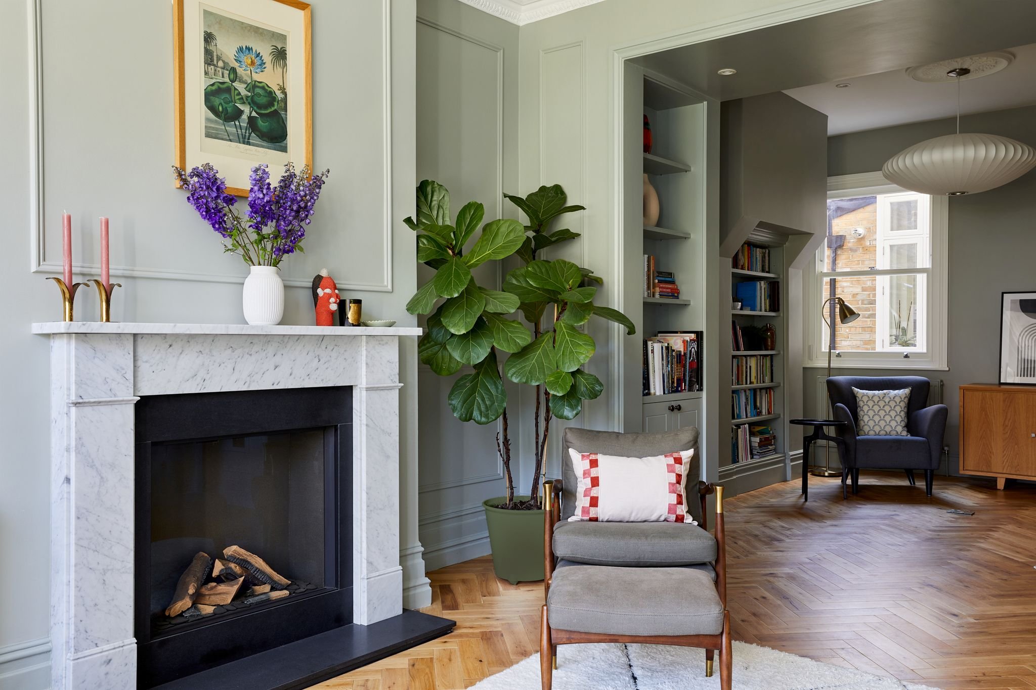 Period living room with marble fireplace, wall panelling and open sightline through to a book-lined snug