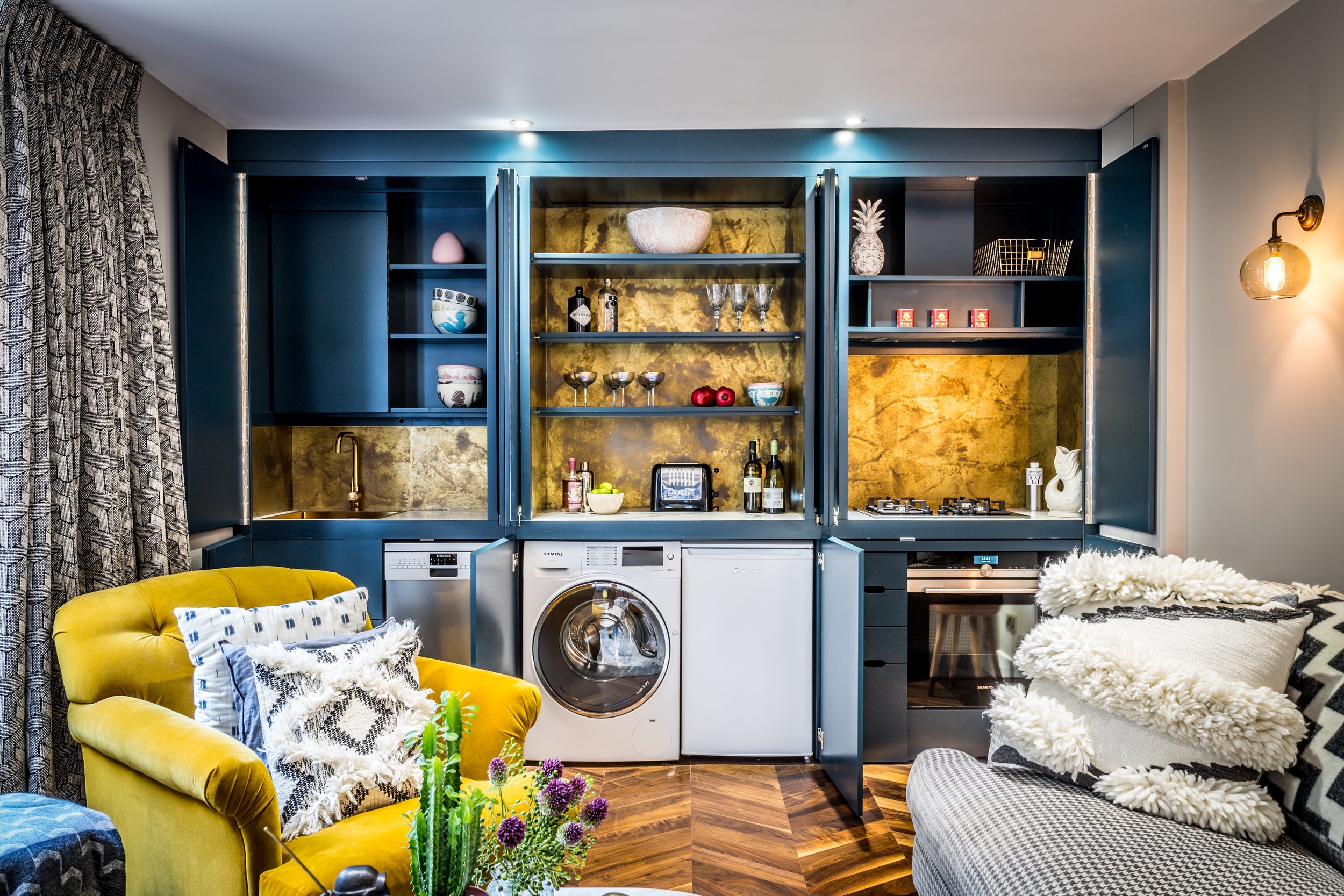 Fully concealed kitchen hidden behind joinery doors with sink, hob, oven and washing machine, a space-saving idea for small apartments