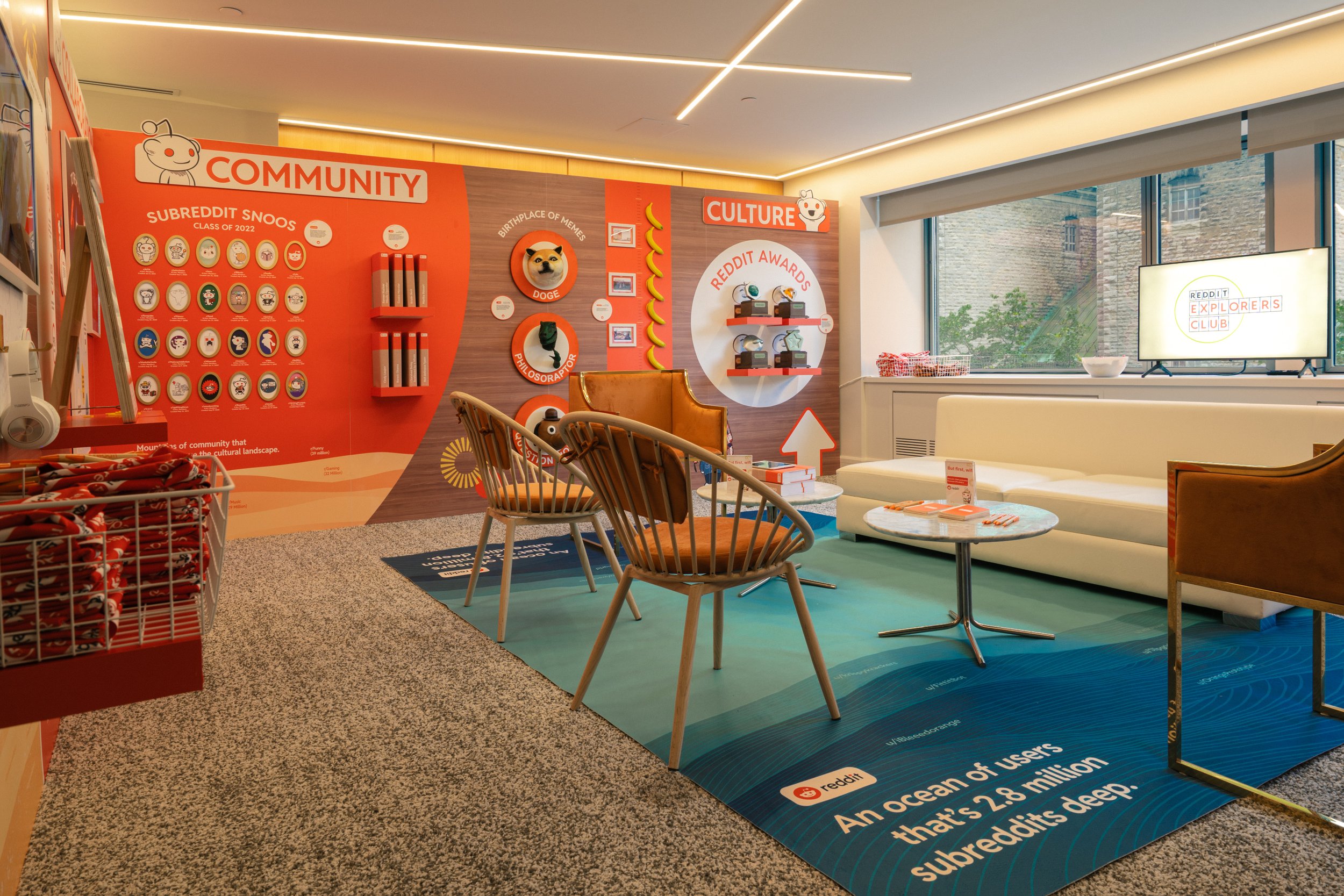 A room featuring Reddit-themed decor with a "Community" wall displaying various subreddit icons and "Culture" wall showing Reddit awards, captured by SquareLoop.