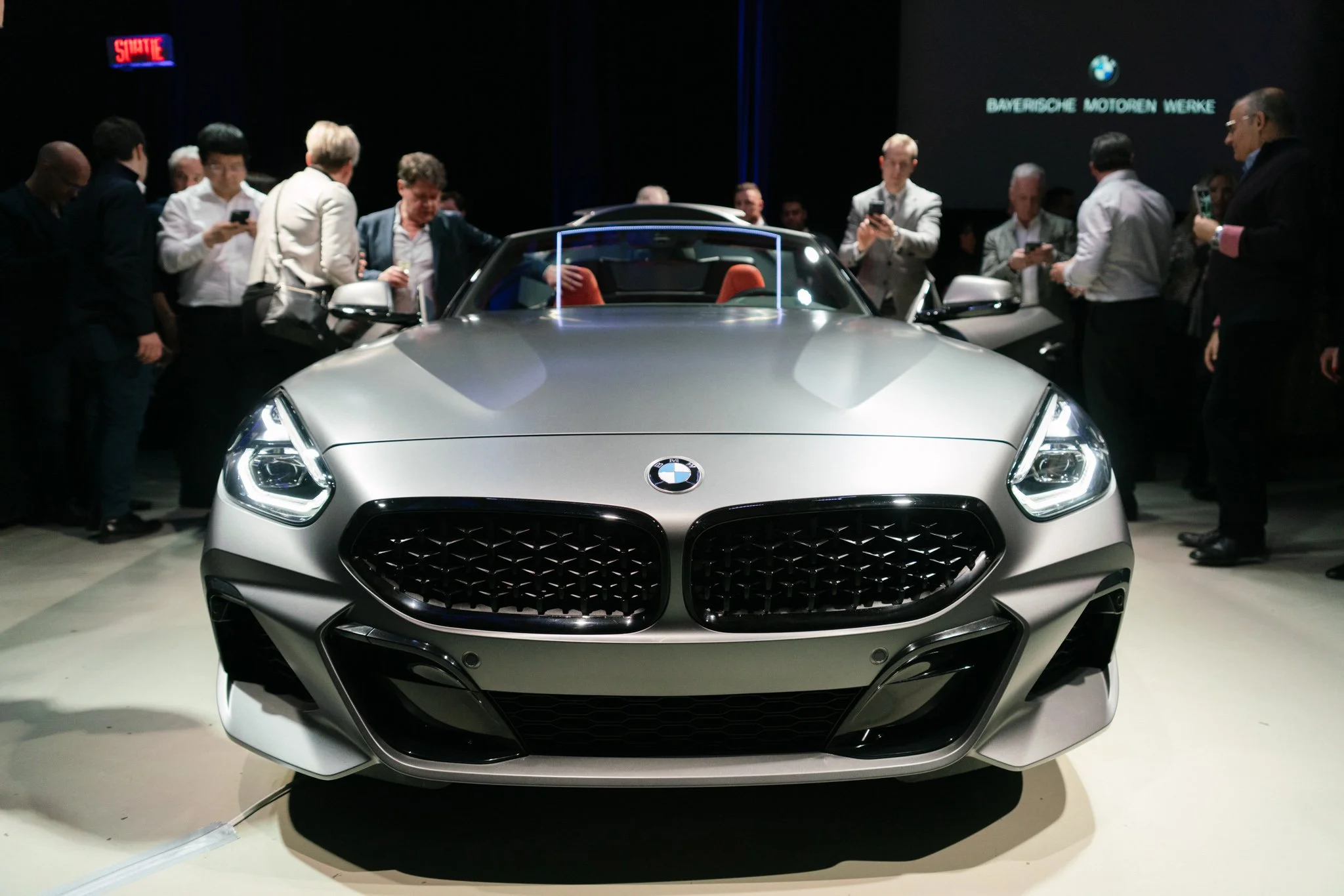 Front view of a silver BMW convertible at a car show with people gathered around captured by Squareloop.