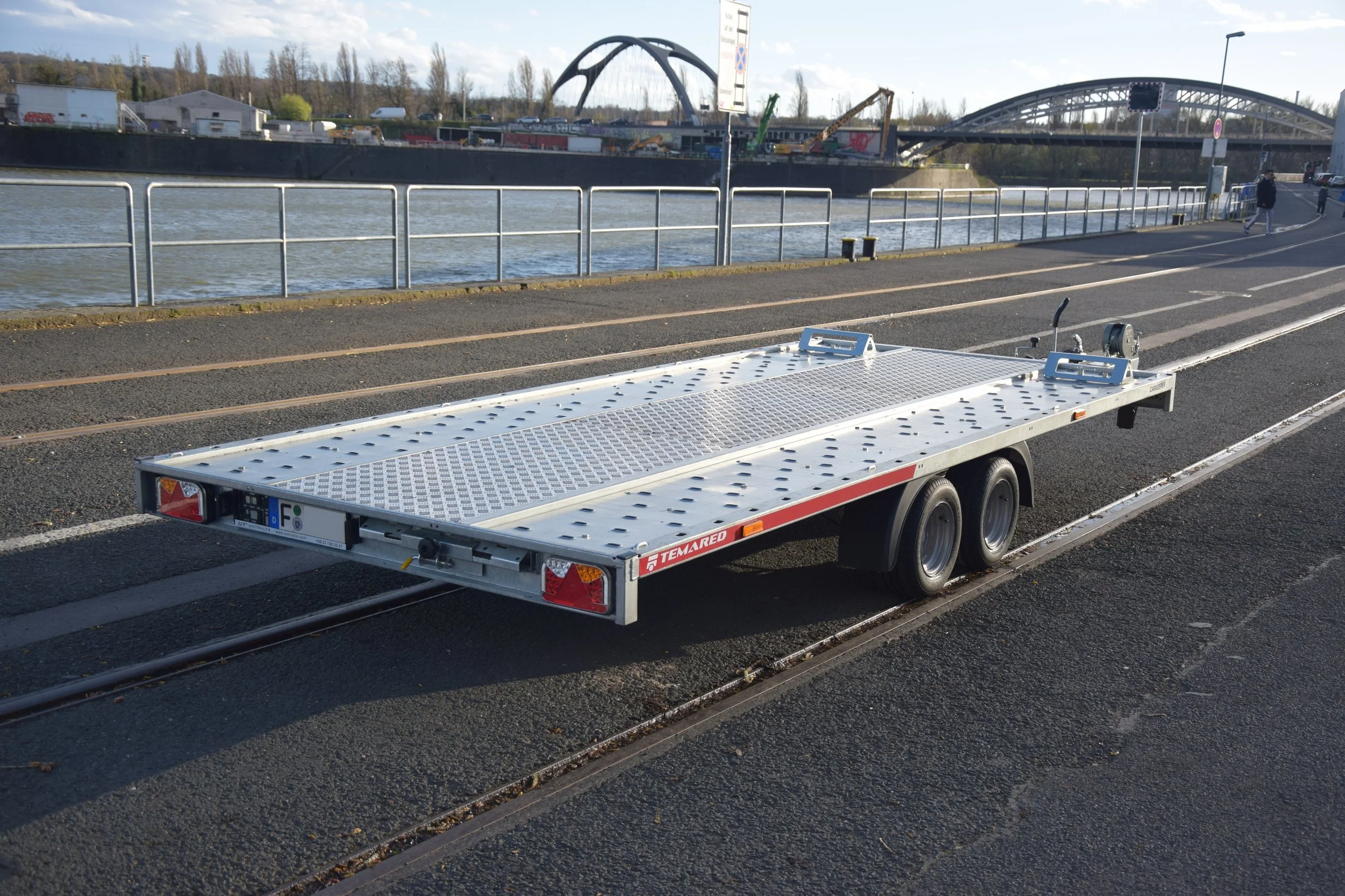Leerer flippertischer Radweg am Fluss mit Brücke und moderner Architektur im Hintergrund