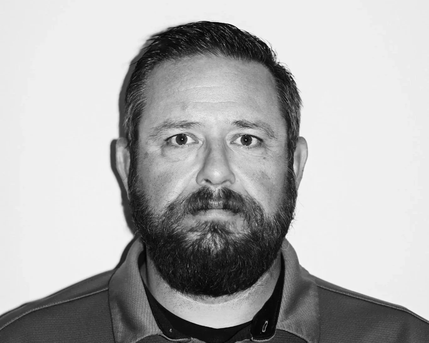 Black and white portrait of a man with short dark hair and a full beard, wearing a polo shirt with "Connect Engineering" and Under Armour logos, against a plain background. A Connect Engineering Employee.
