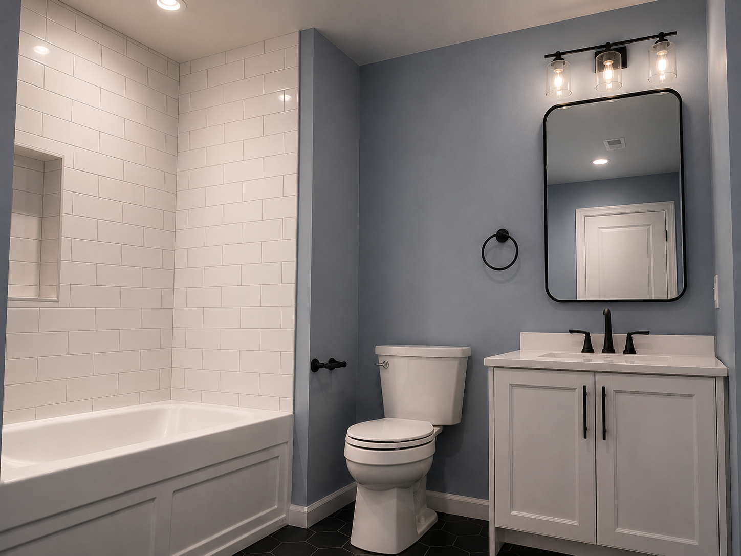 Modern bathroom with subway tile bath, white vanity, black faucet, large mirror, and a toilet. Bathroom Remodels