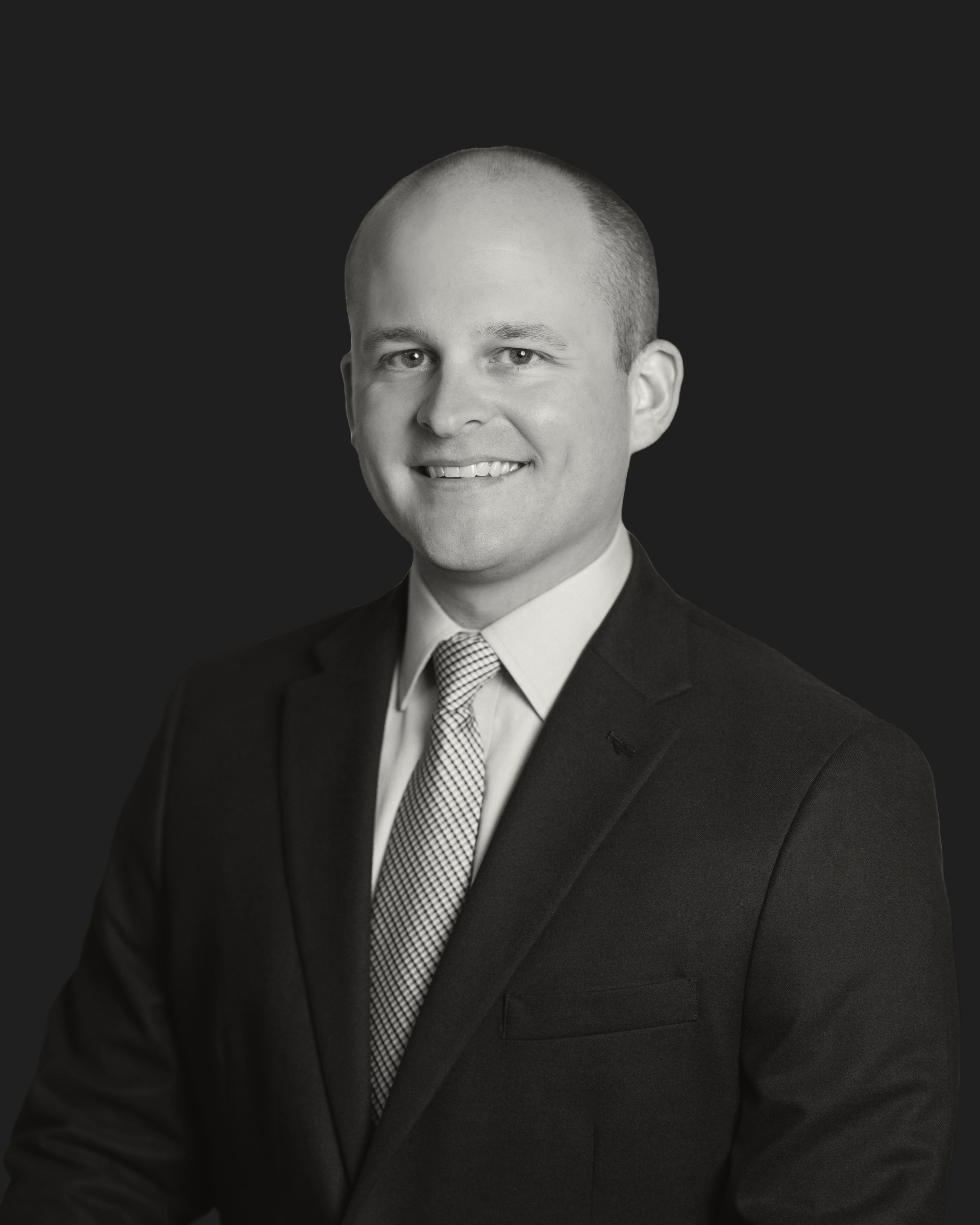 Man in a suit and tie smiling against a dark background