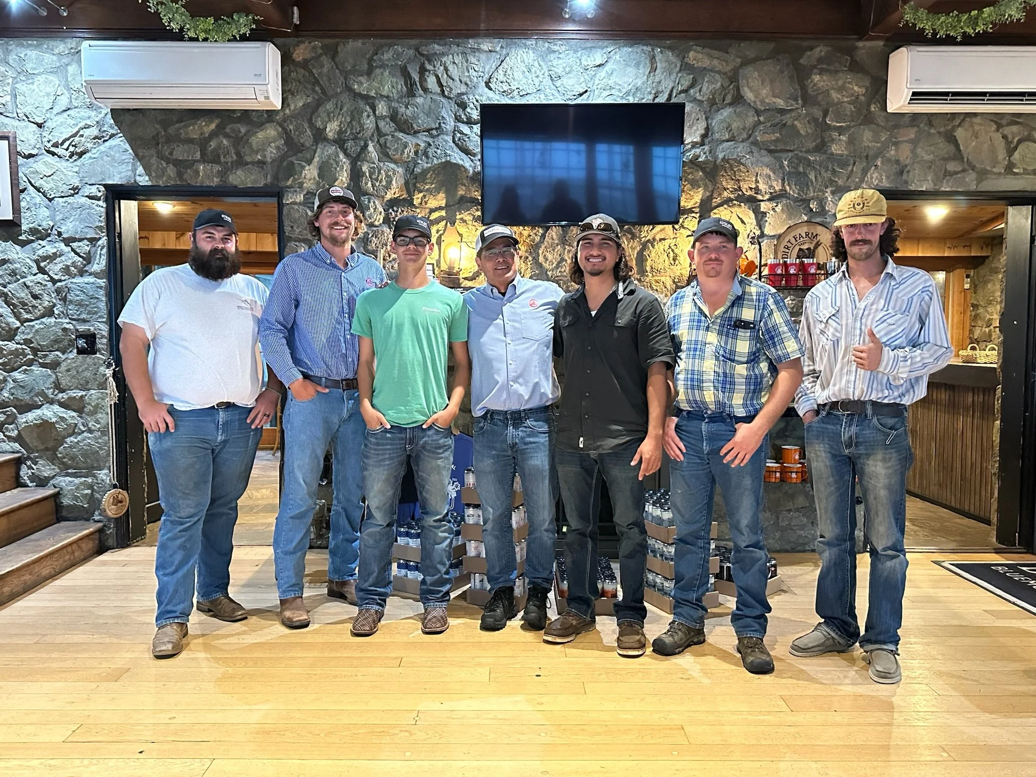 Seven men from the Audley Farm Cattle Team, standing in a row inside Dirt Farm Brewing in Bluemont, smiling at the camera.
