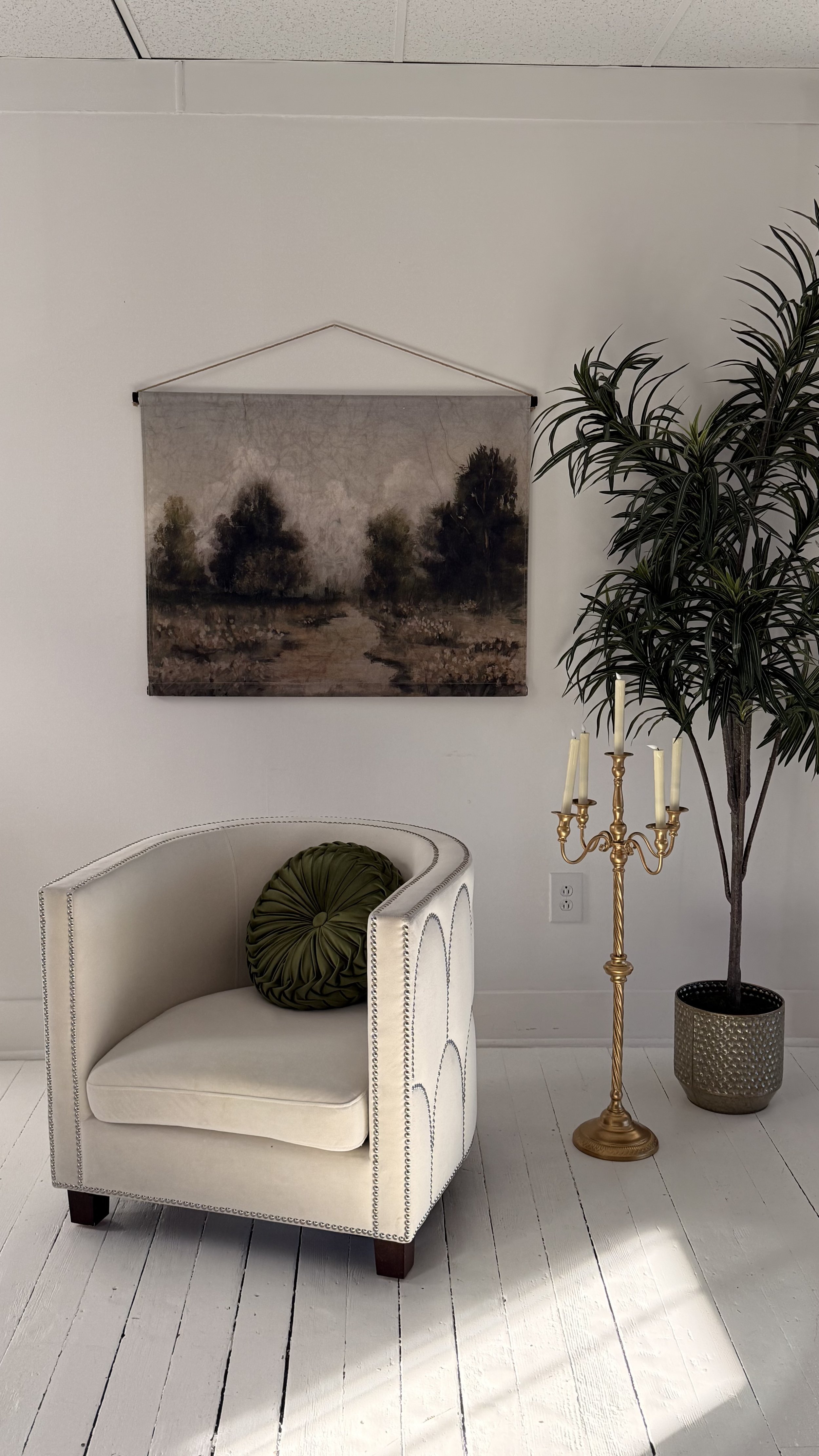 white studed chair, gold candle holder, plant and a moody forest wall tapestry make up this photographer set perfect for boudoir or branding