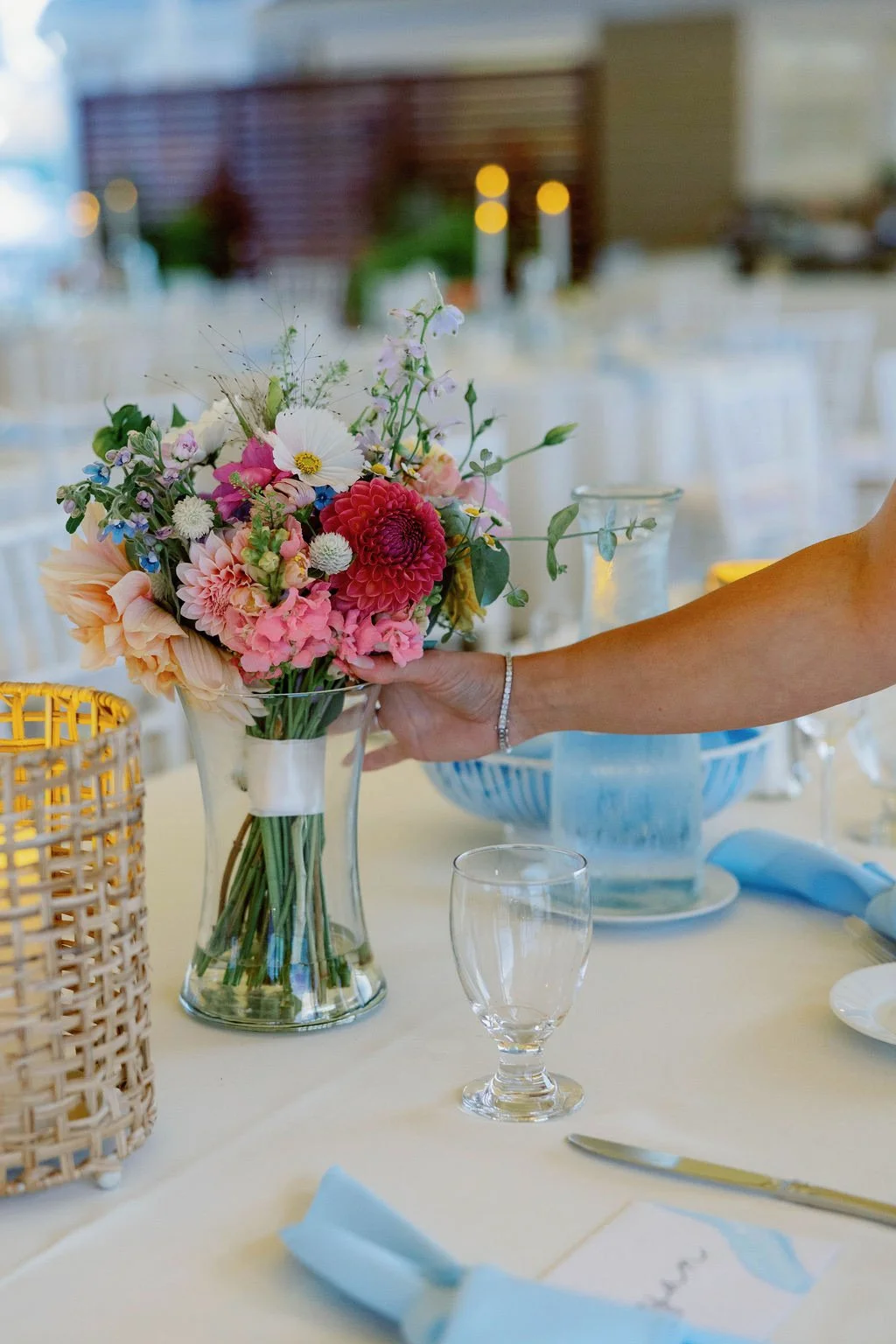 Colorful bridal bouquet being placed upon a head table.