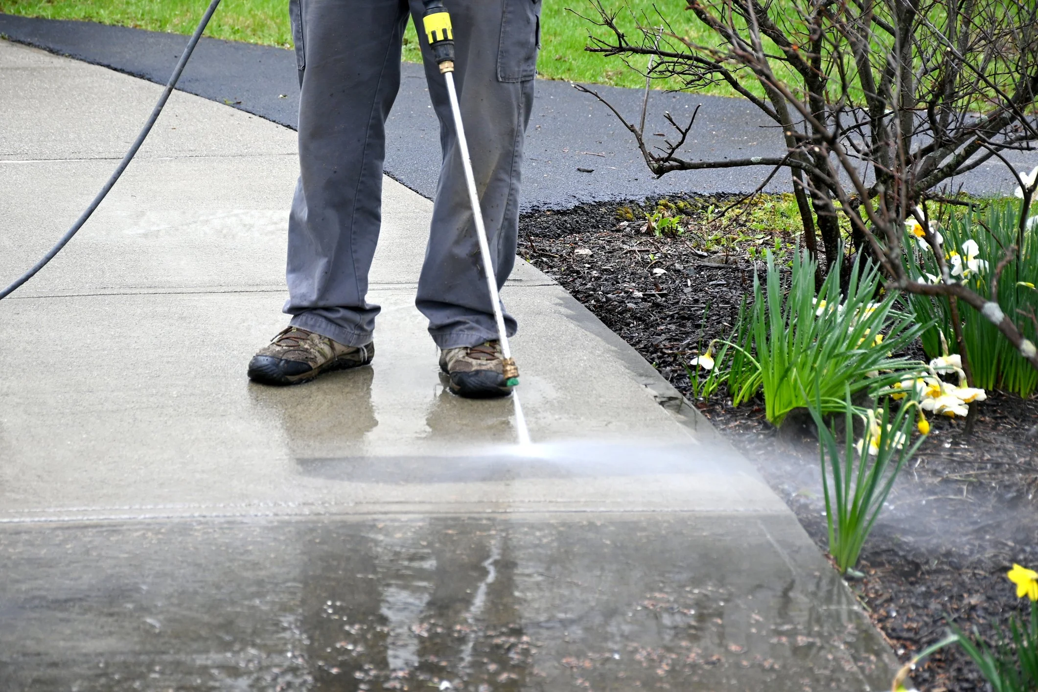 A person pressure washing a concrete driveway and patio in Omaha, Nebraska.