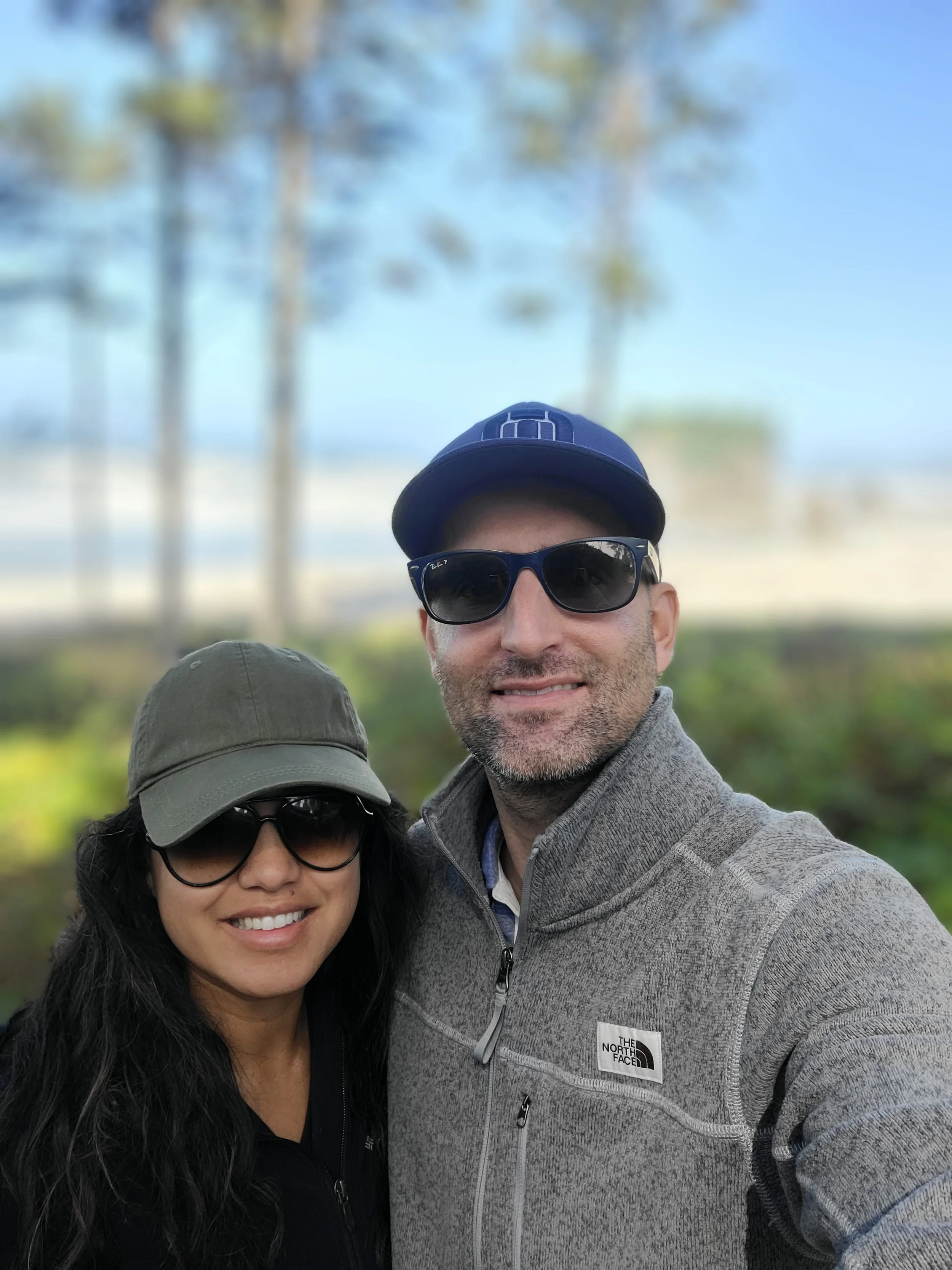 A smiling couple with sunglasses posing for a picture near a home in Omaha, Nebraska.